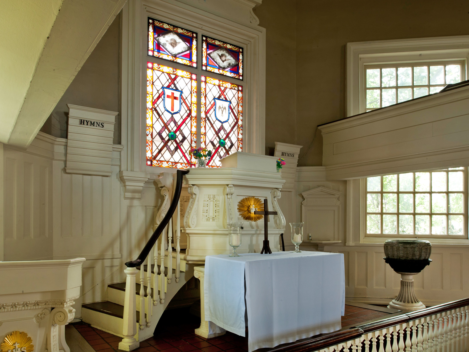 A color photo of the interior of Gloria Dei Church showing the pulpit and a stained glass window.