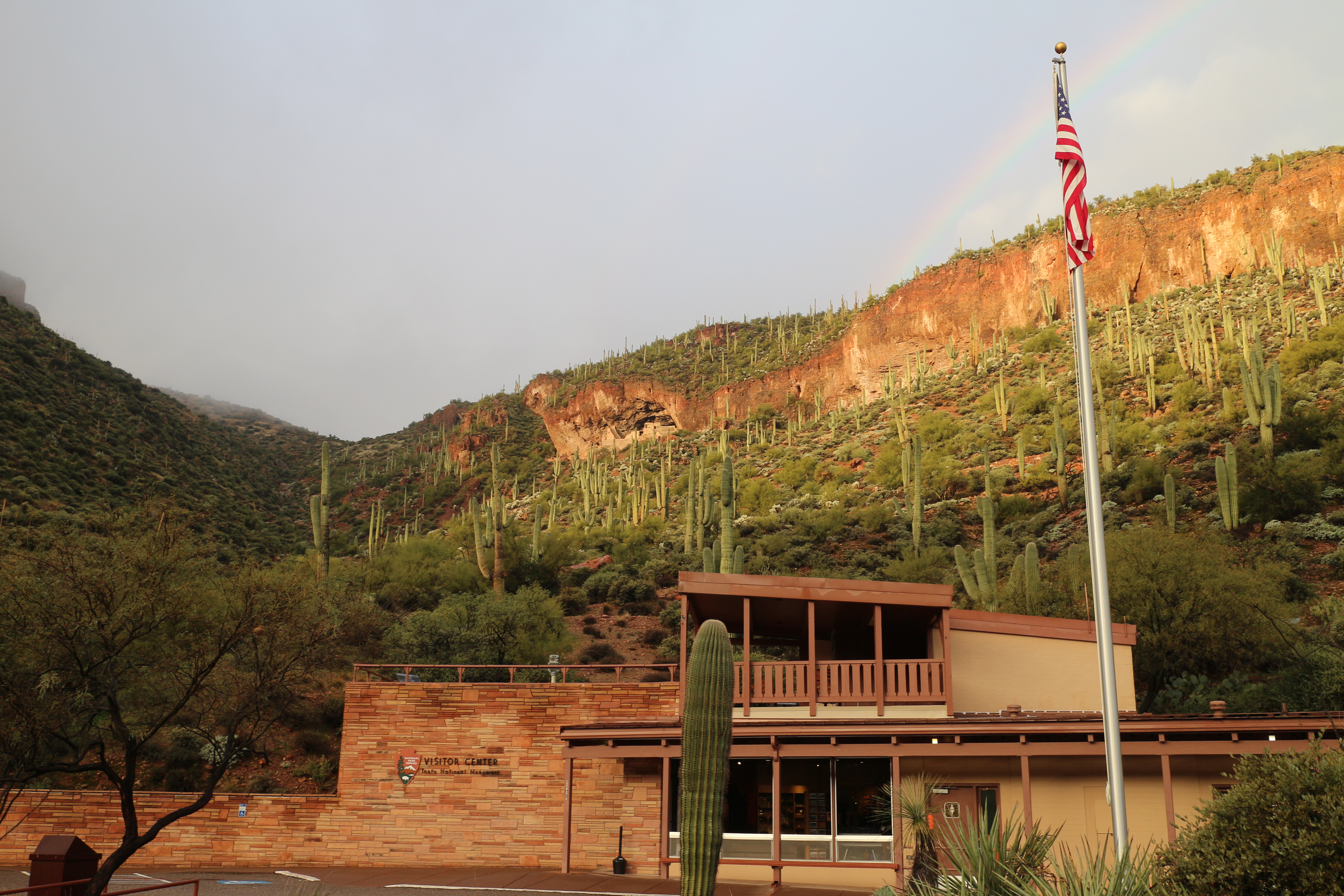 Visitor Center with cliff dwelling and a rainbow in the background.