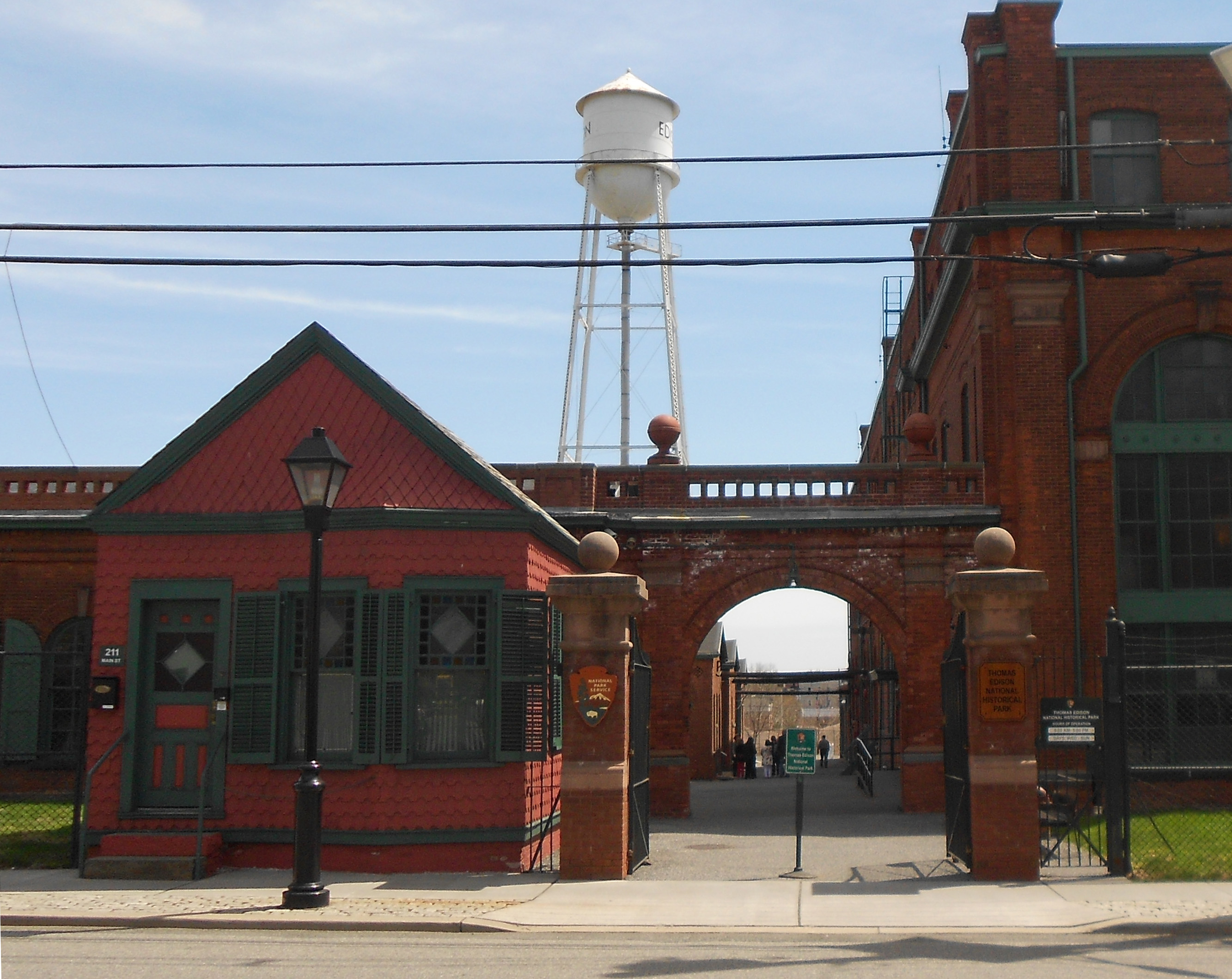 Small red building next to large brick building with a water tower in the background.