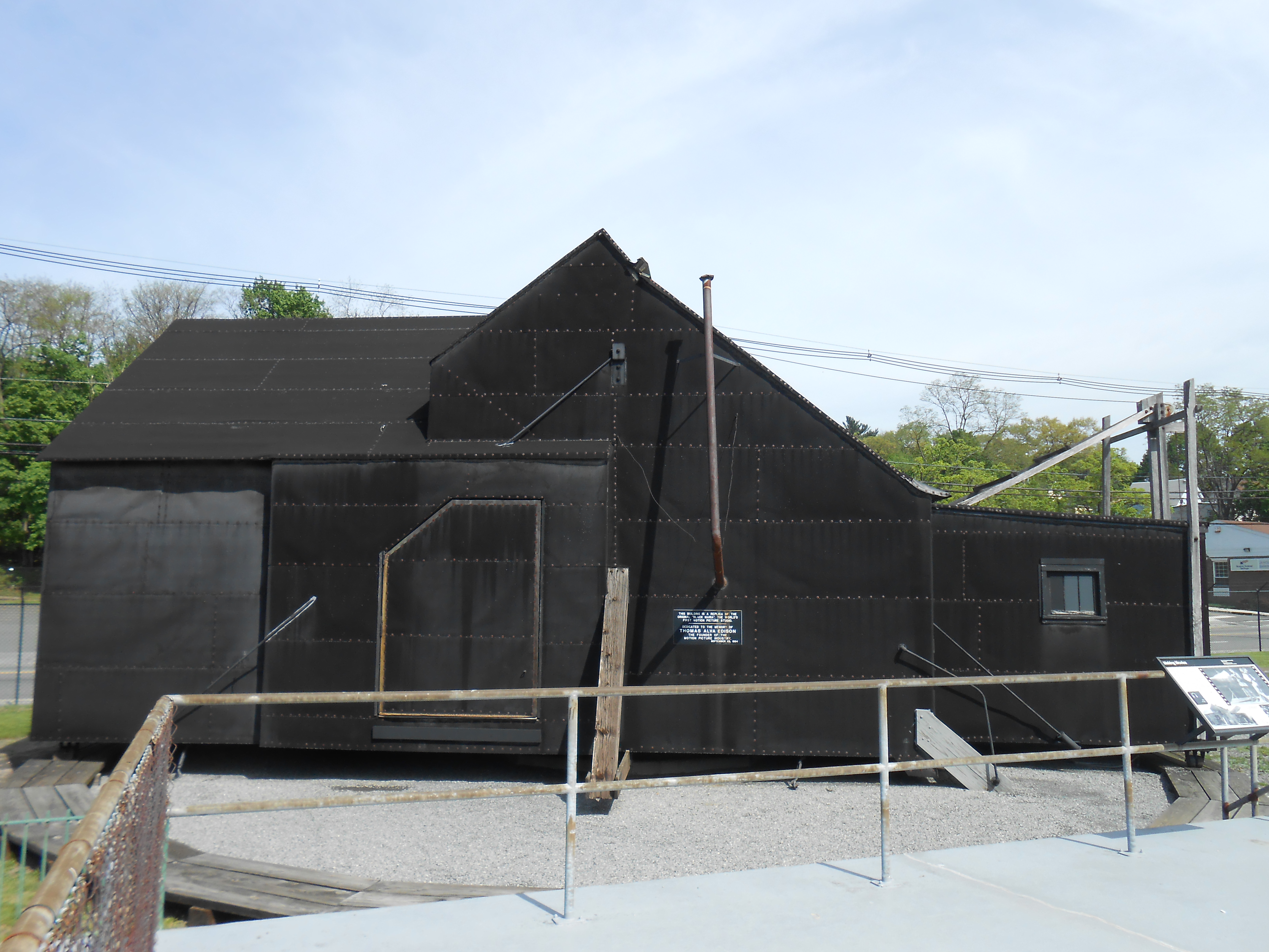 Large black building covered in tar paper surrounded by a barrier fence