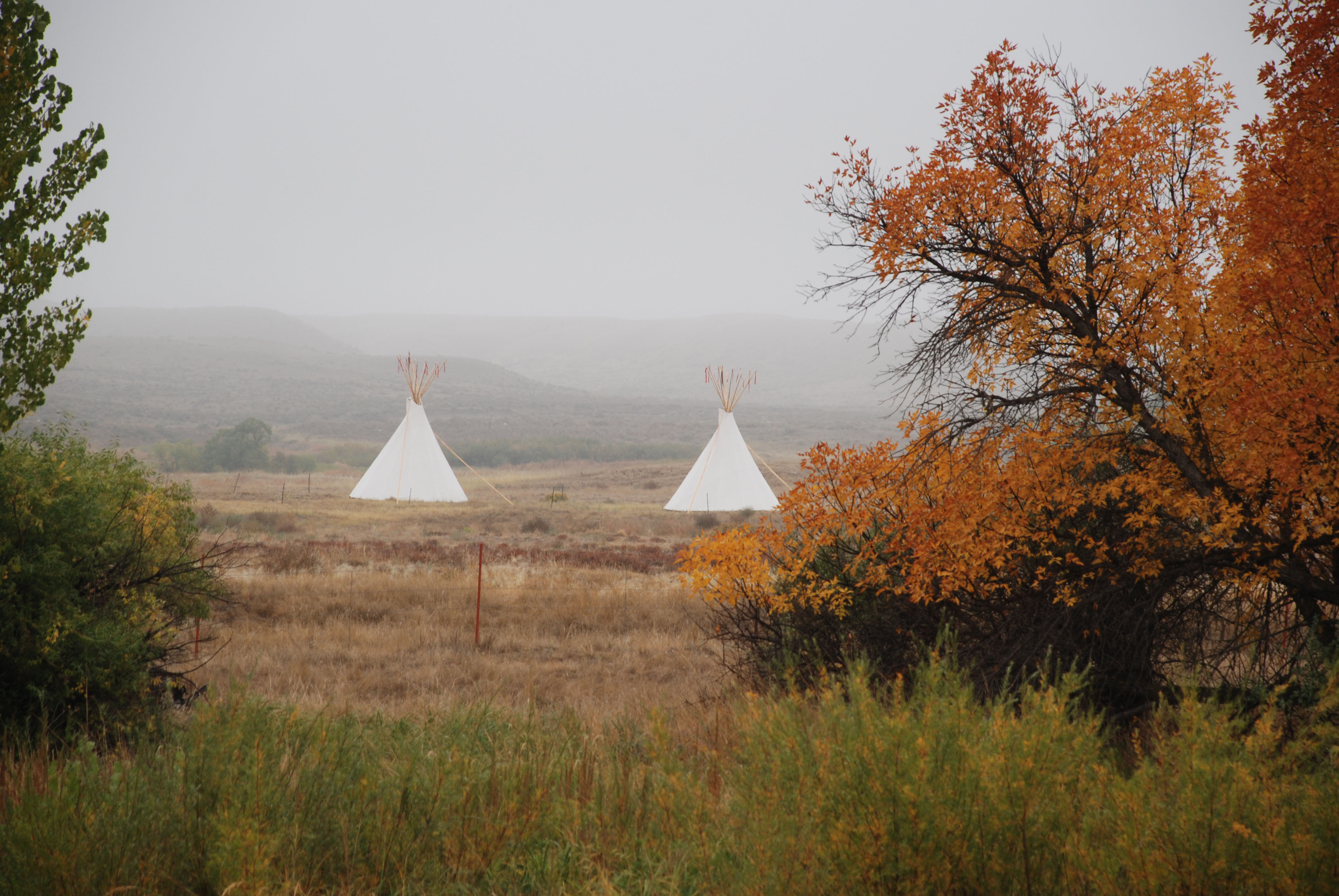 Two tipis across the Laramie River from the fort in fall
