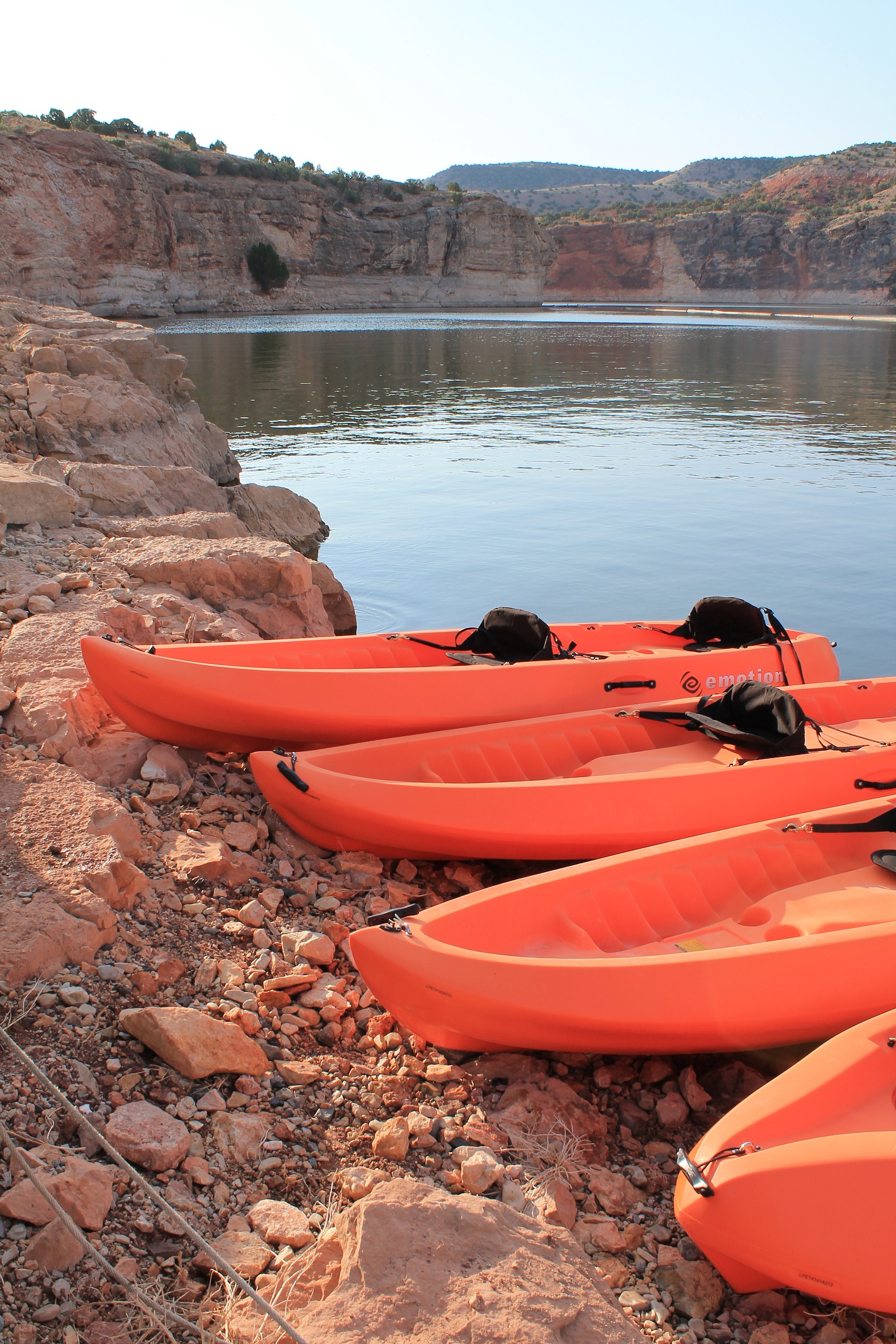 Four orange kayaks laying with their tips on the red rocks at Barry's Landing.