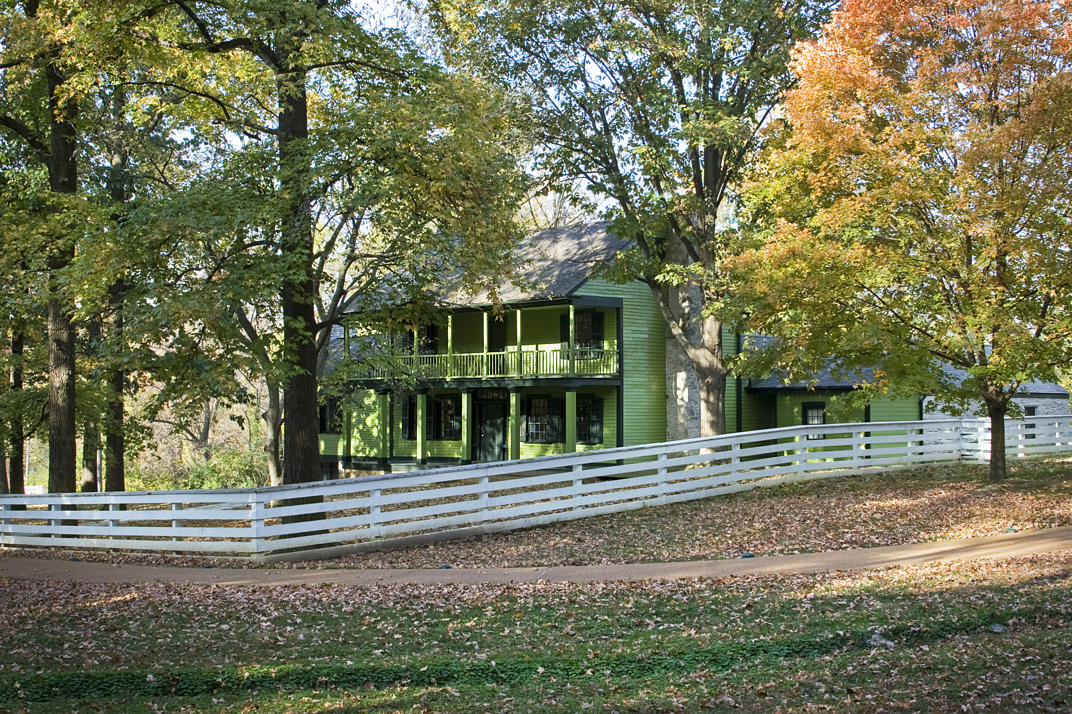 View of house with fence. Autumn colored leaves on trees