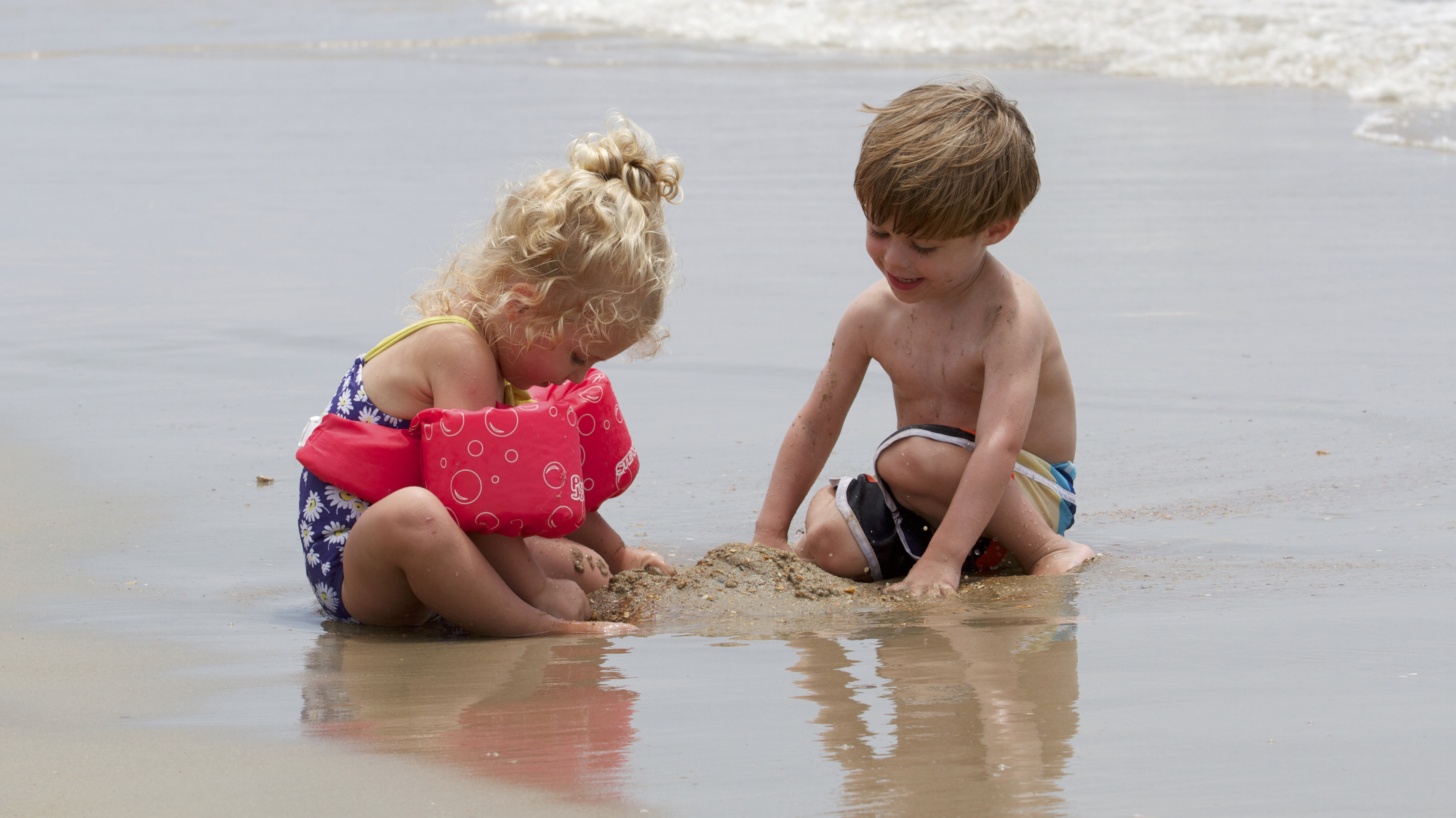 Two kids play in the sand.