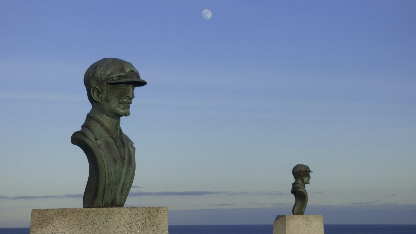 Copper busts of the two brothers with the moon visible in the blue sky.