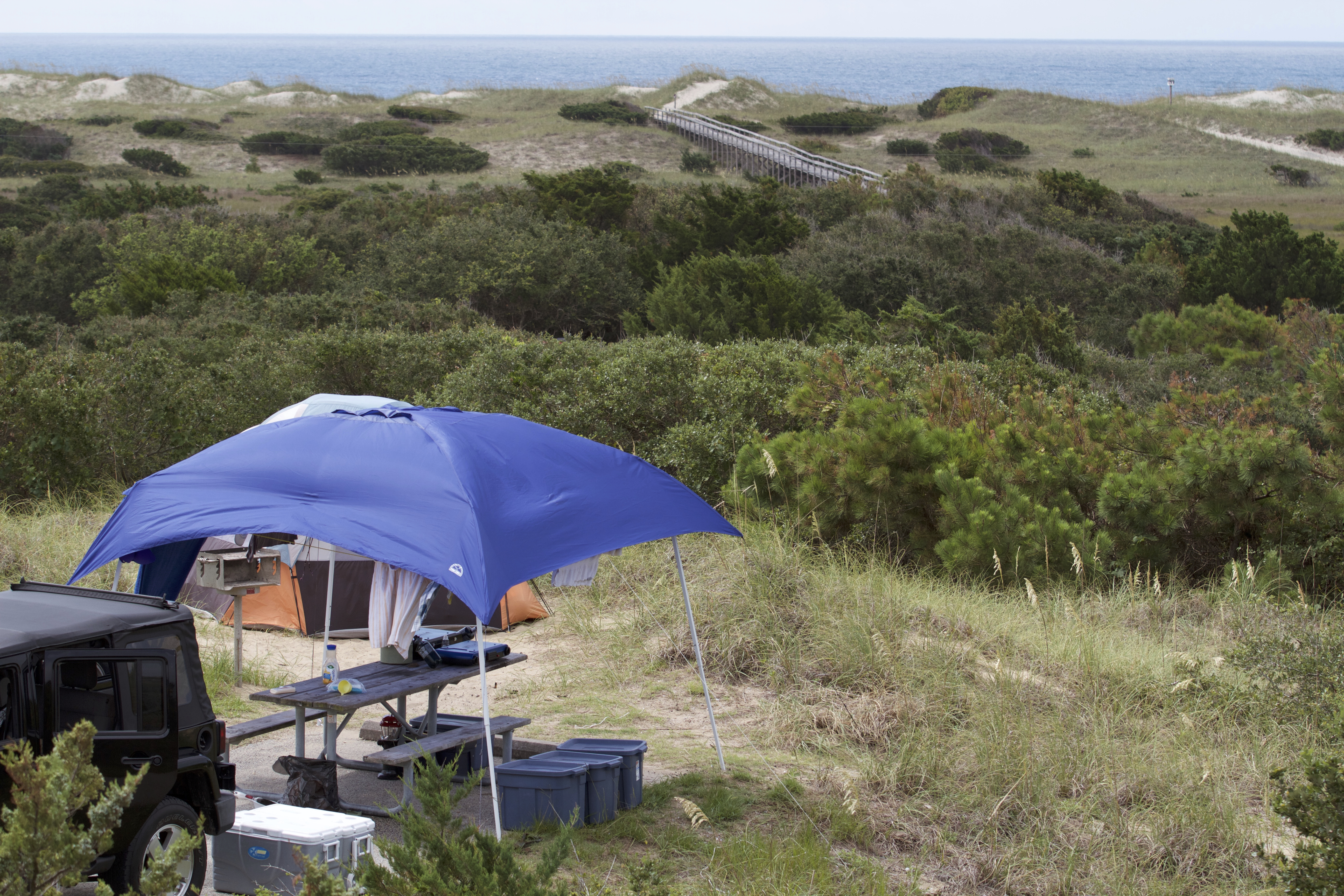 Canopy, tent, and vehicle at a camp site looking over the dune field at Frisco Campground.