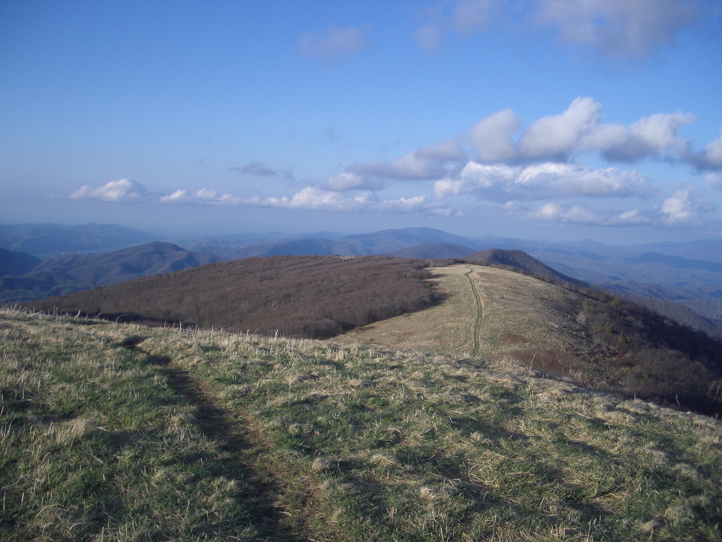 The Appalachian Trail runs across a mountain ridge line with views to the horizon of mountain range.