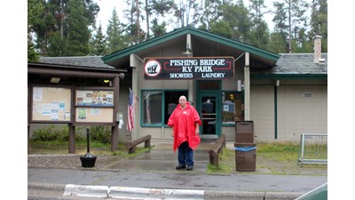 Man dressed inraincoat standing in front of building.