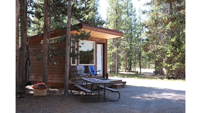 small cabin for overnight lodging shaded by conifers