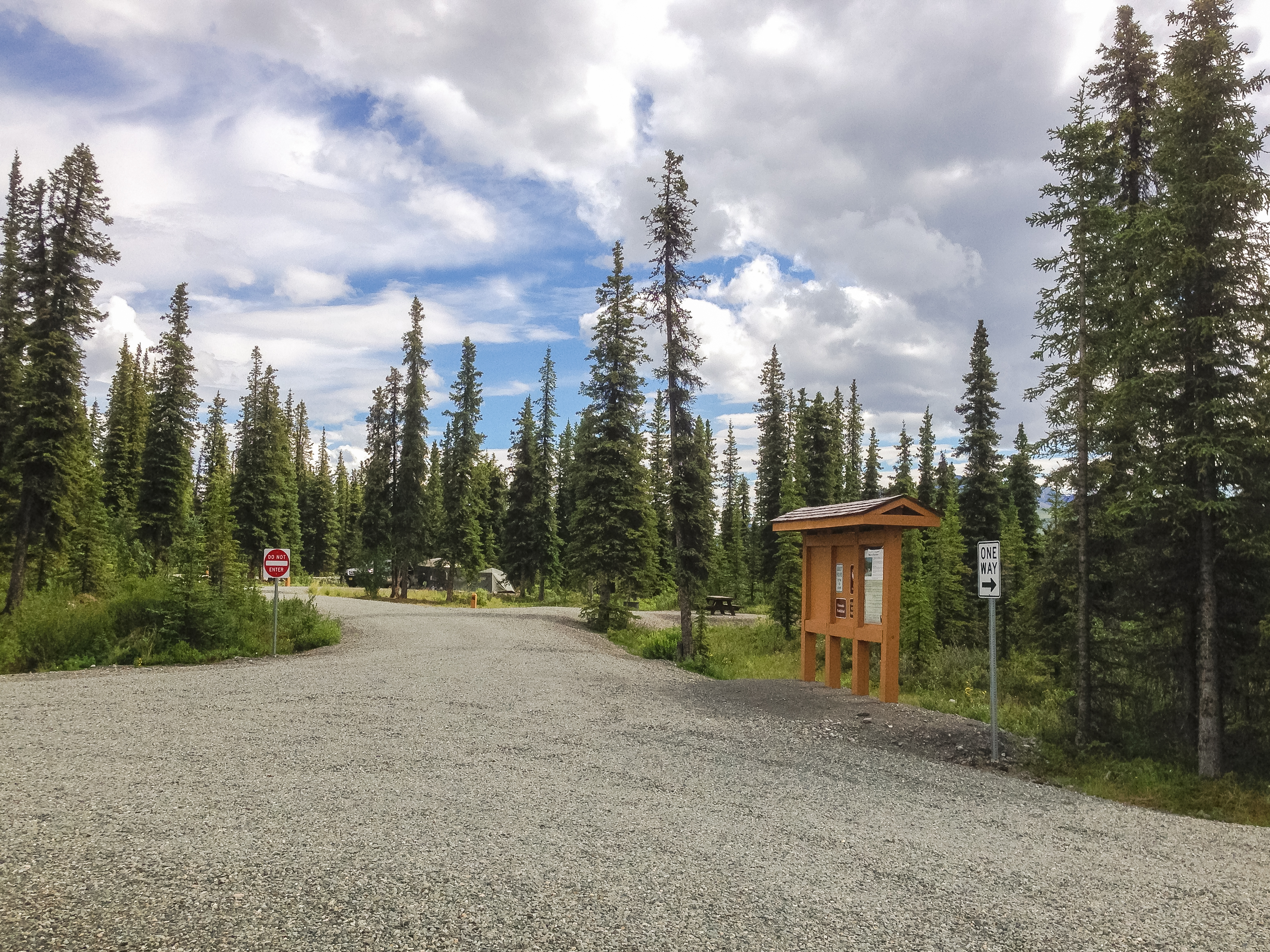 View of campground road and campsites with forest and cloudy skies in the background.
