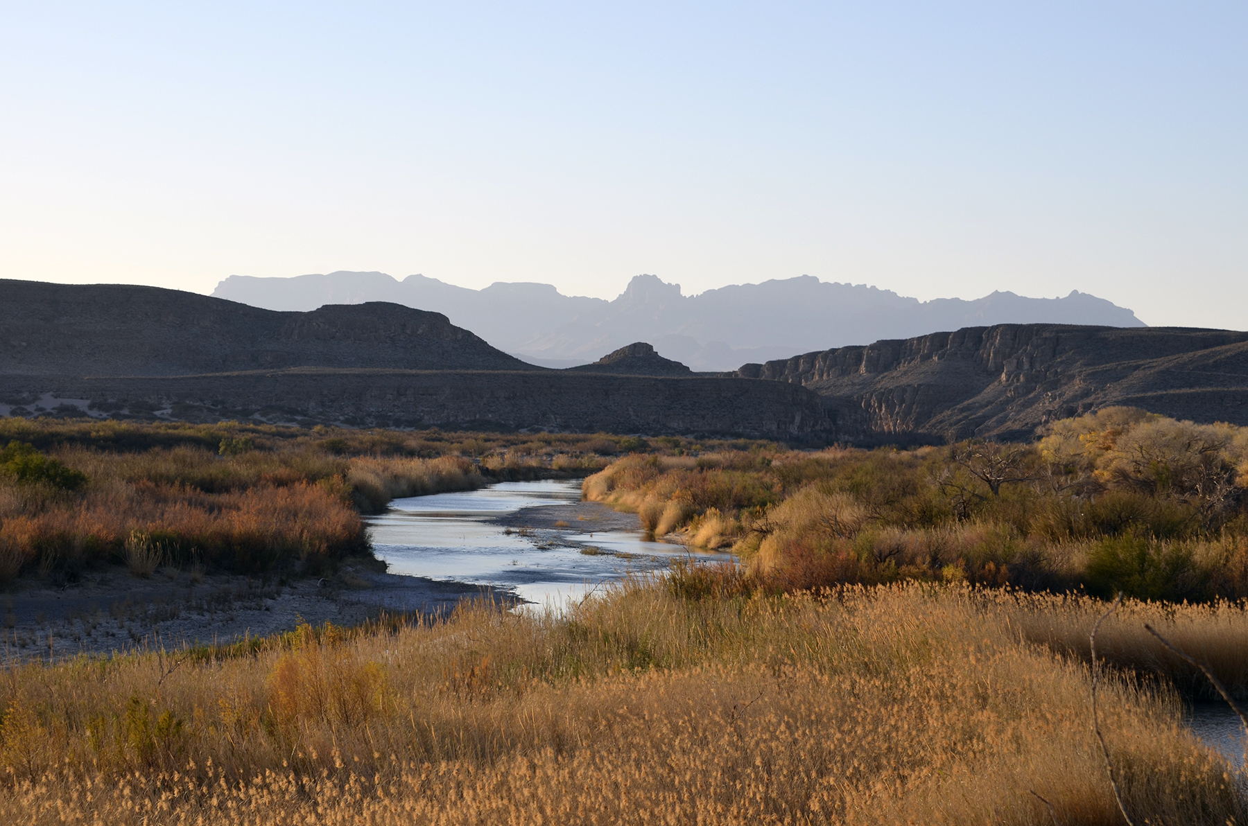 A desert river with a backdrop of mountains in the distance.