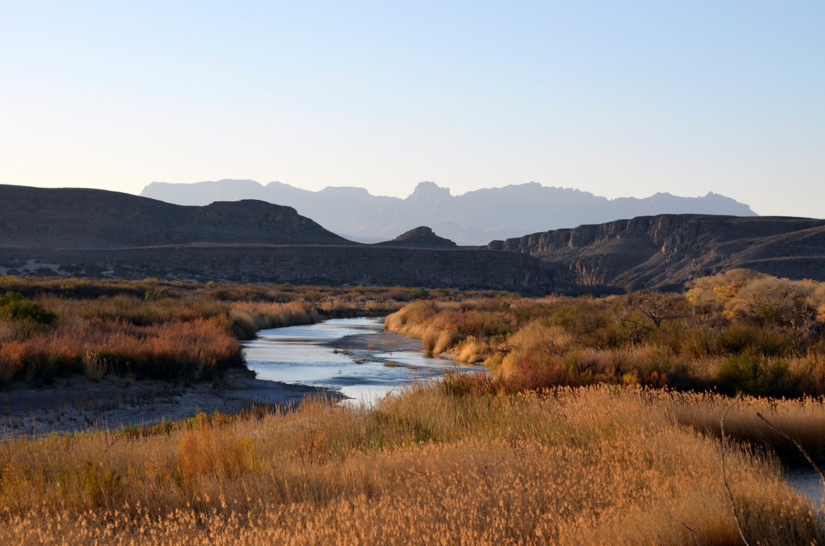 A desert river with a backdrop of mountains in the distance. 