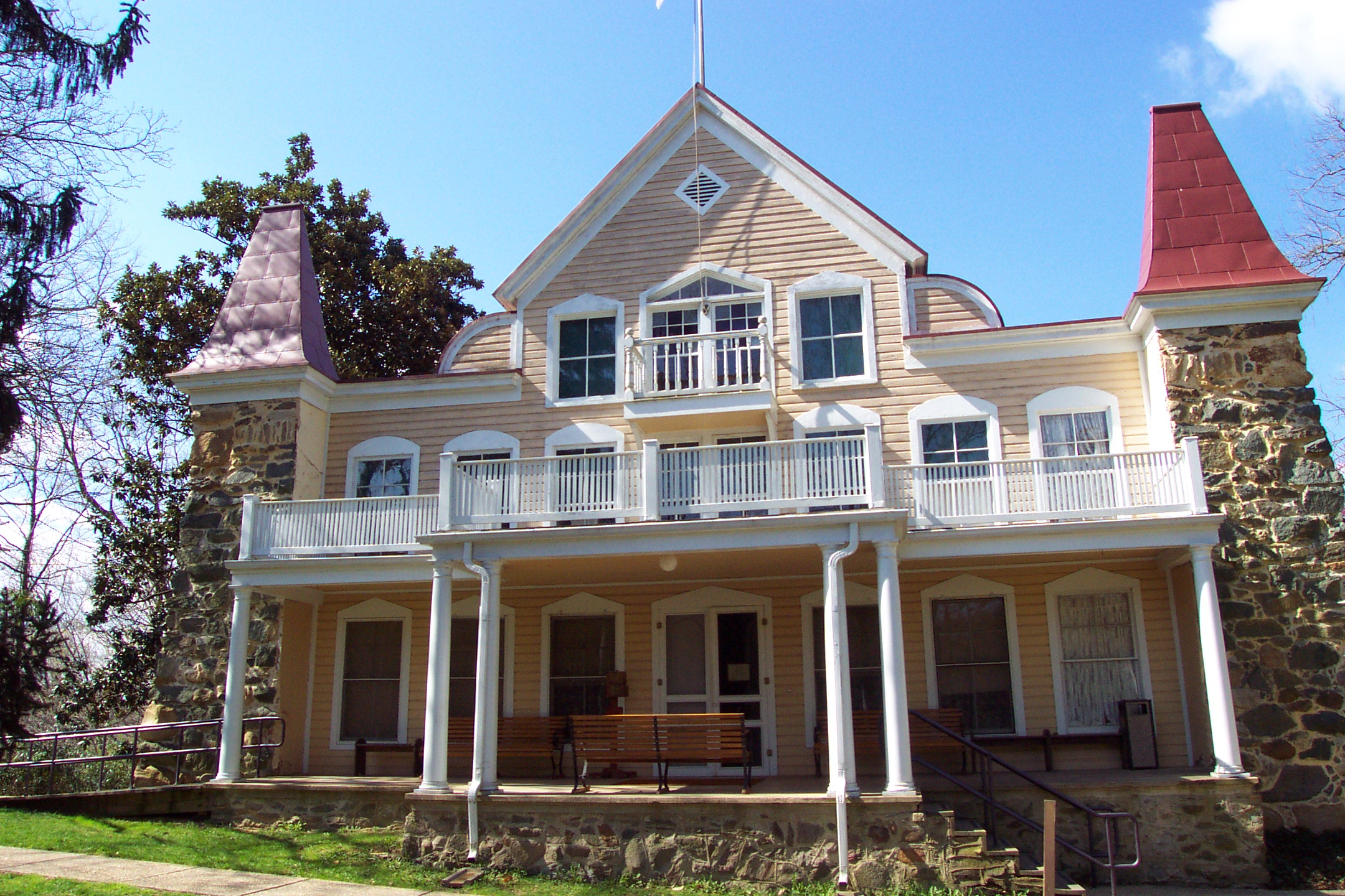 two and half story wooden frame house with double porch and stone corner posts.