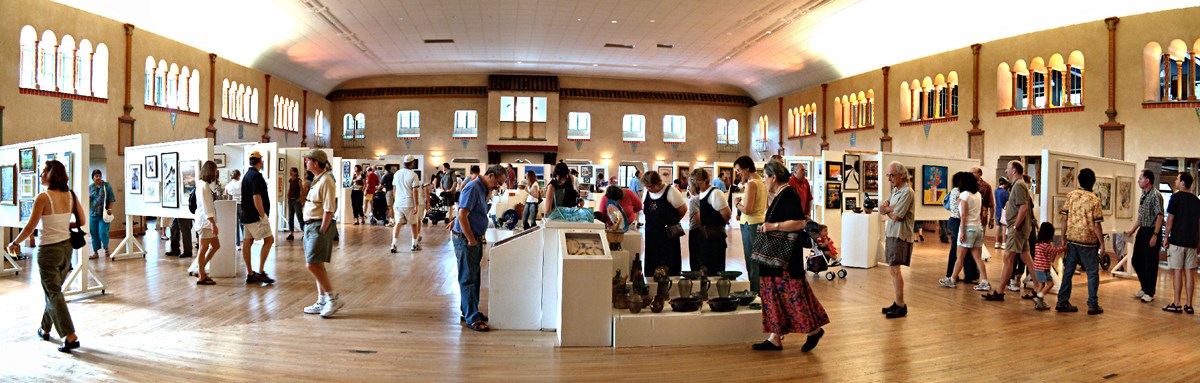 people walking around large room during art show