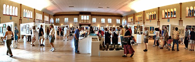 people walking around large room during art show