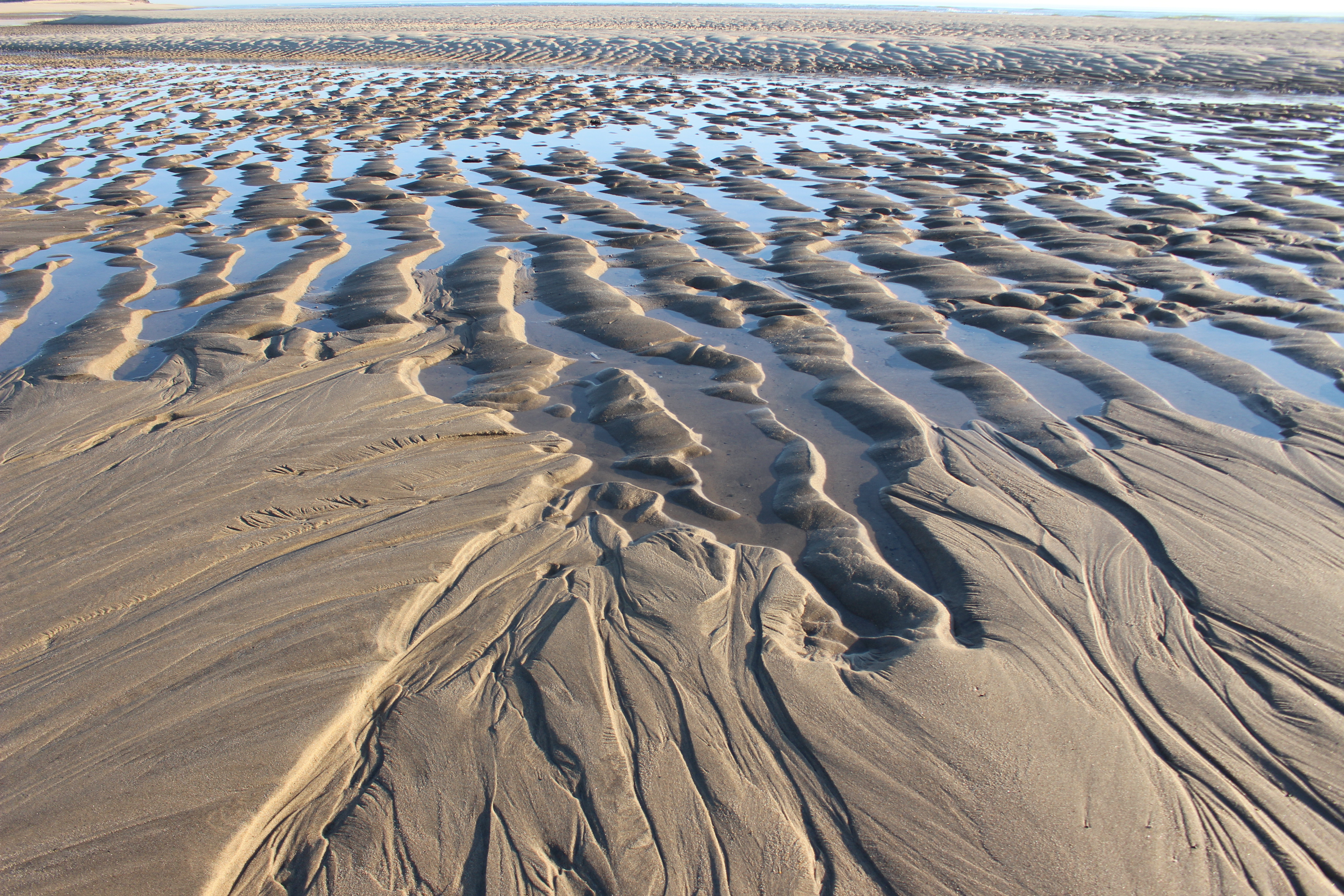 Low tide exposes rippled ridges of sand and water.