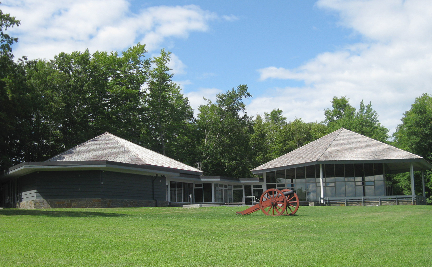 A building shaped slightly like two low, adjoining mushrooms sits on a lush green lawn.