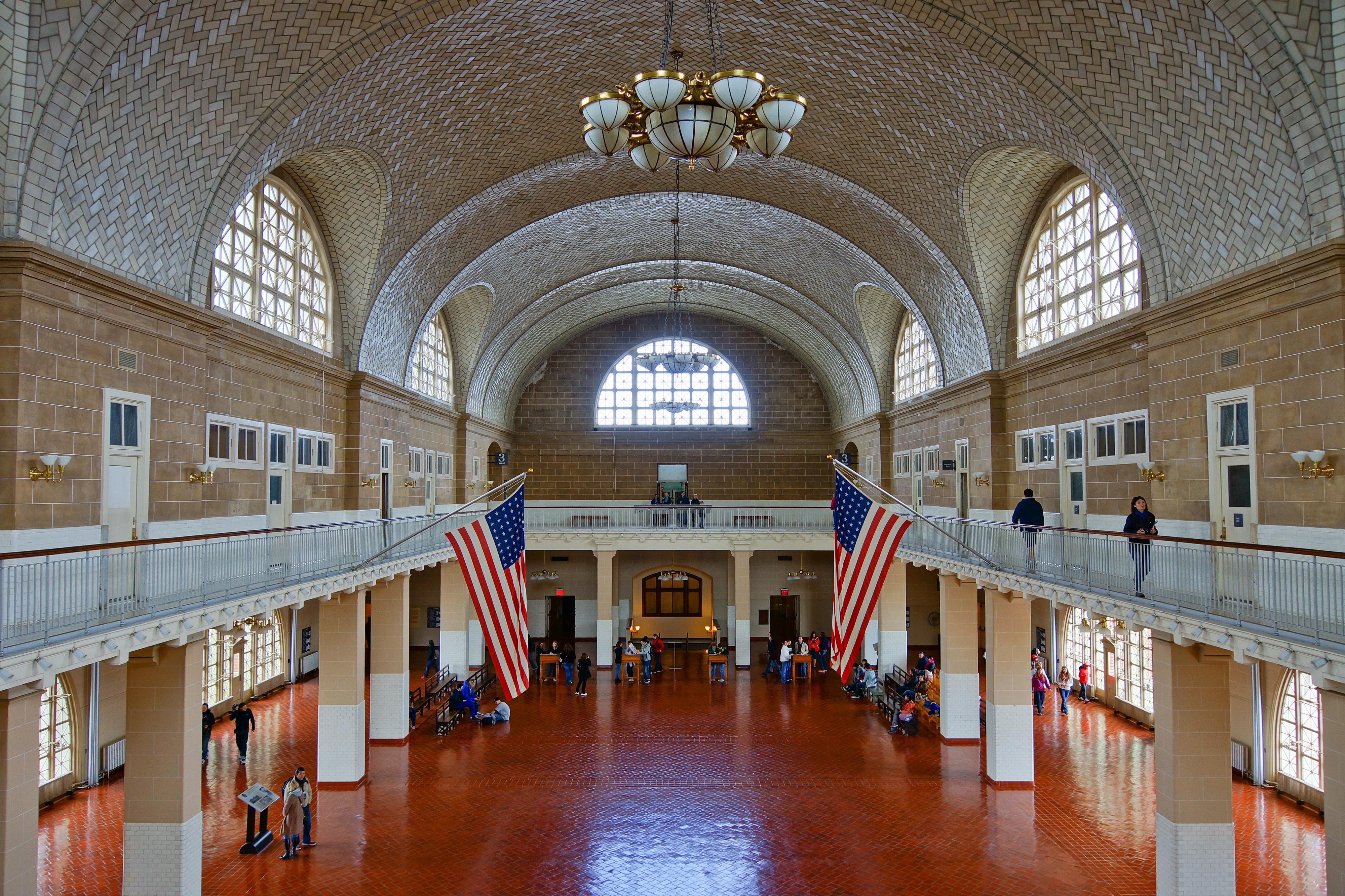 Great Hall has terra cotta-colored tile floor, a balcony, large arched windows, and vaulted ceiling