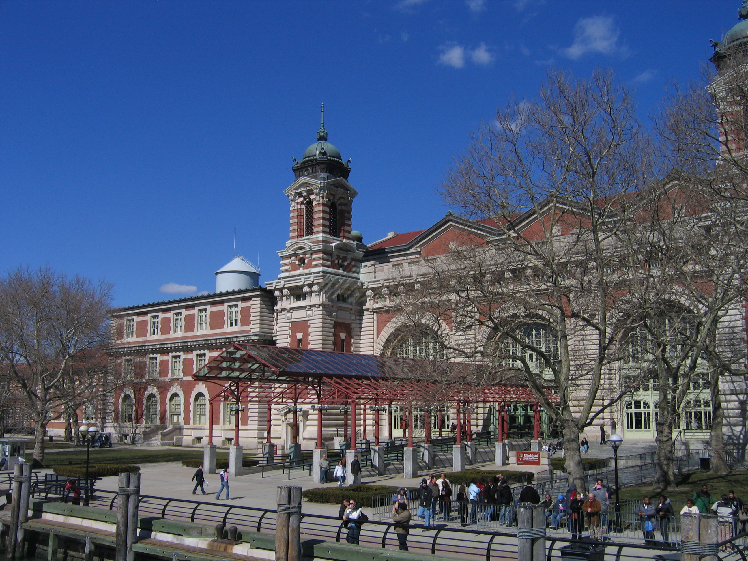 Brick and limestone building with maroon canopy leading to entrance.