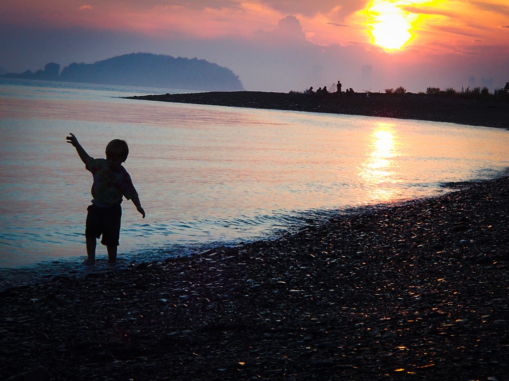 A child dancing on the beach at dusk