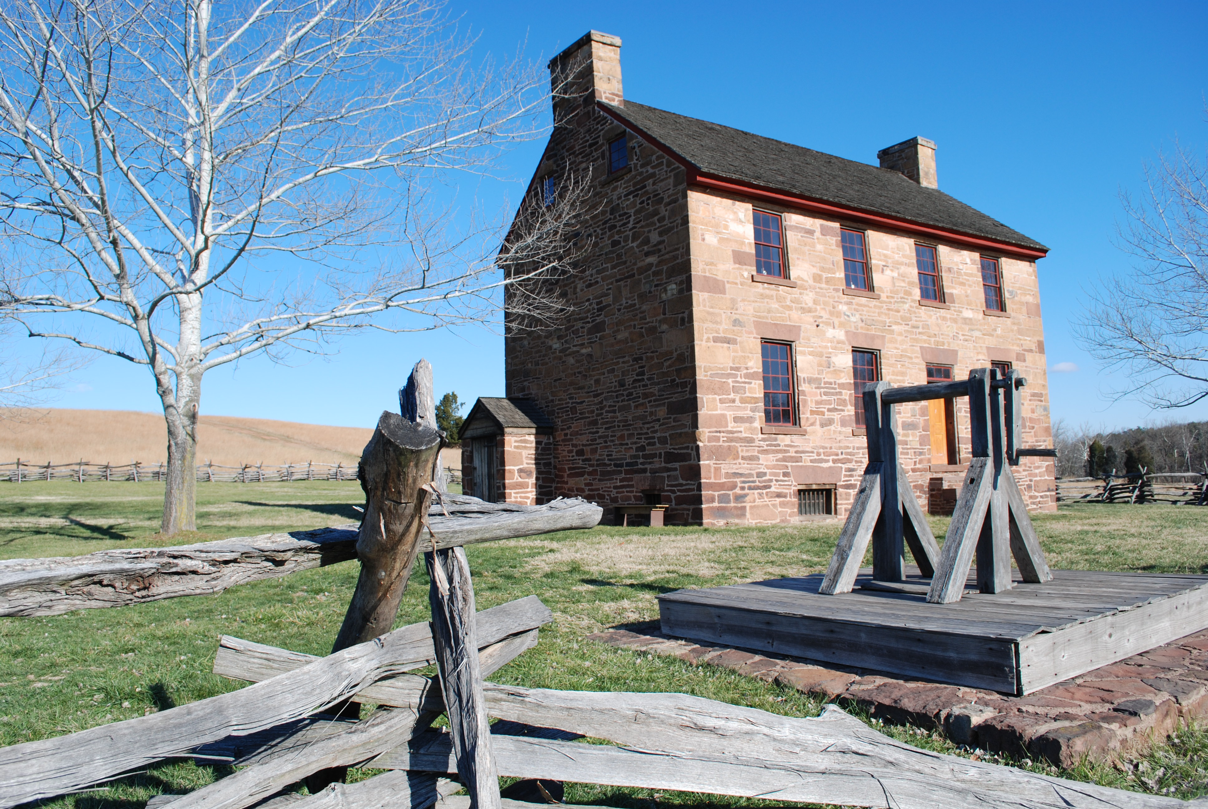 View of Stone House, with worm rail fence and well in front yard.