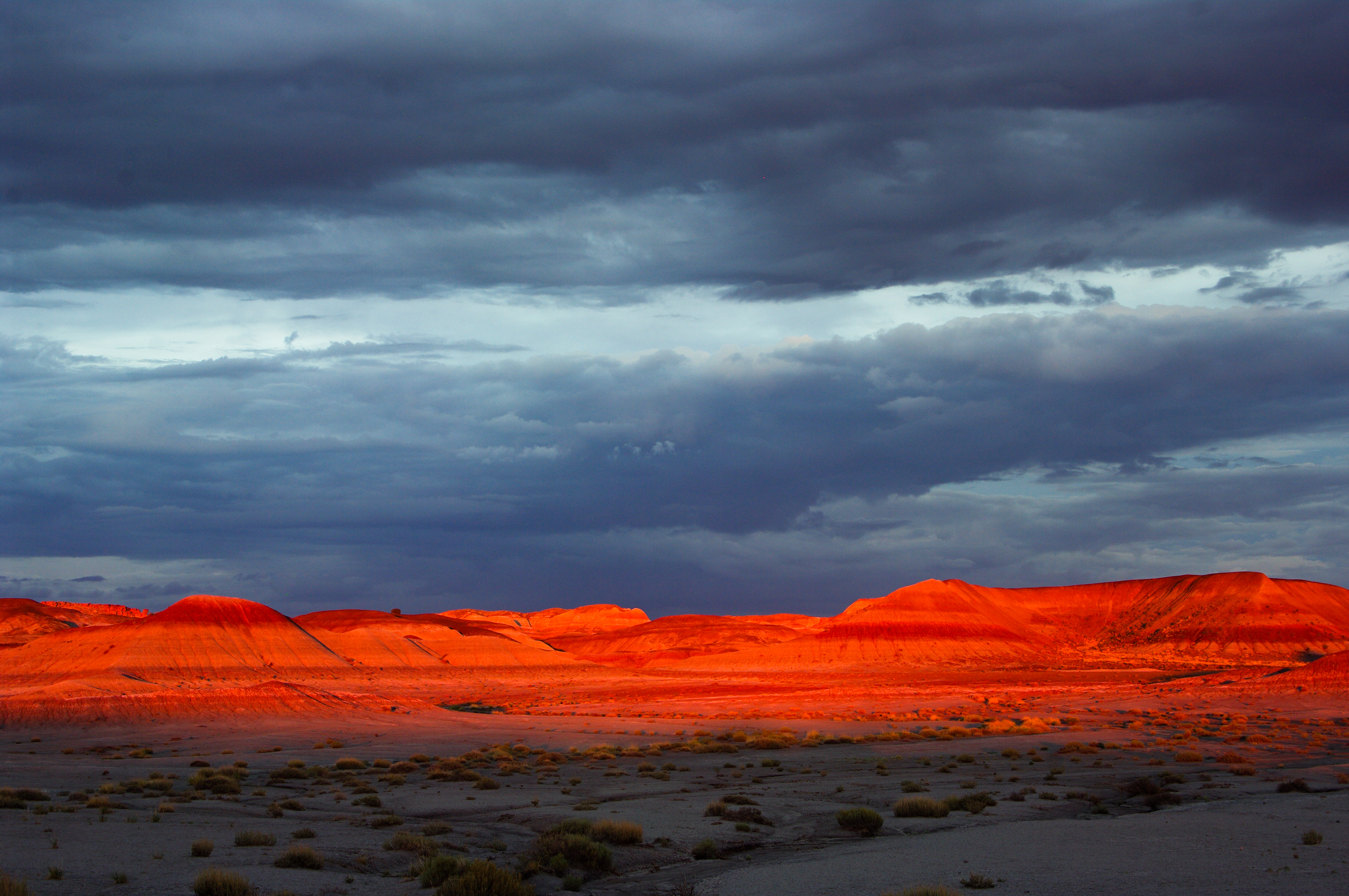 striped badlands glow red in the sunset light at the Tepees