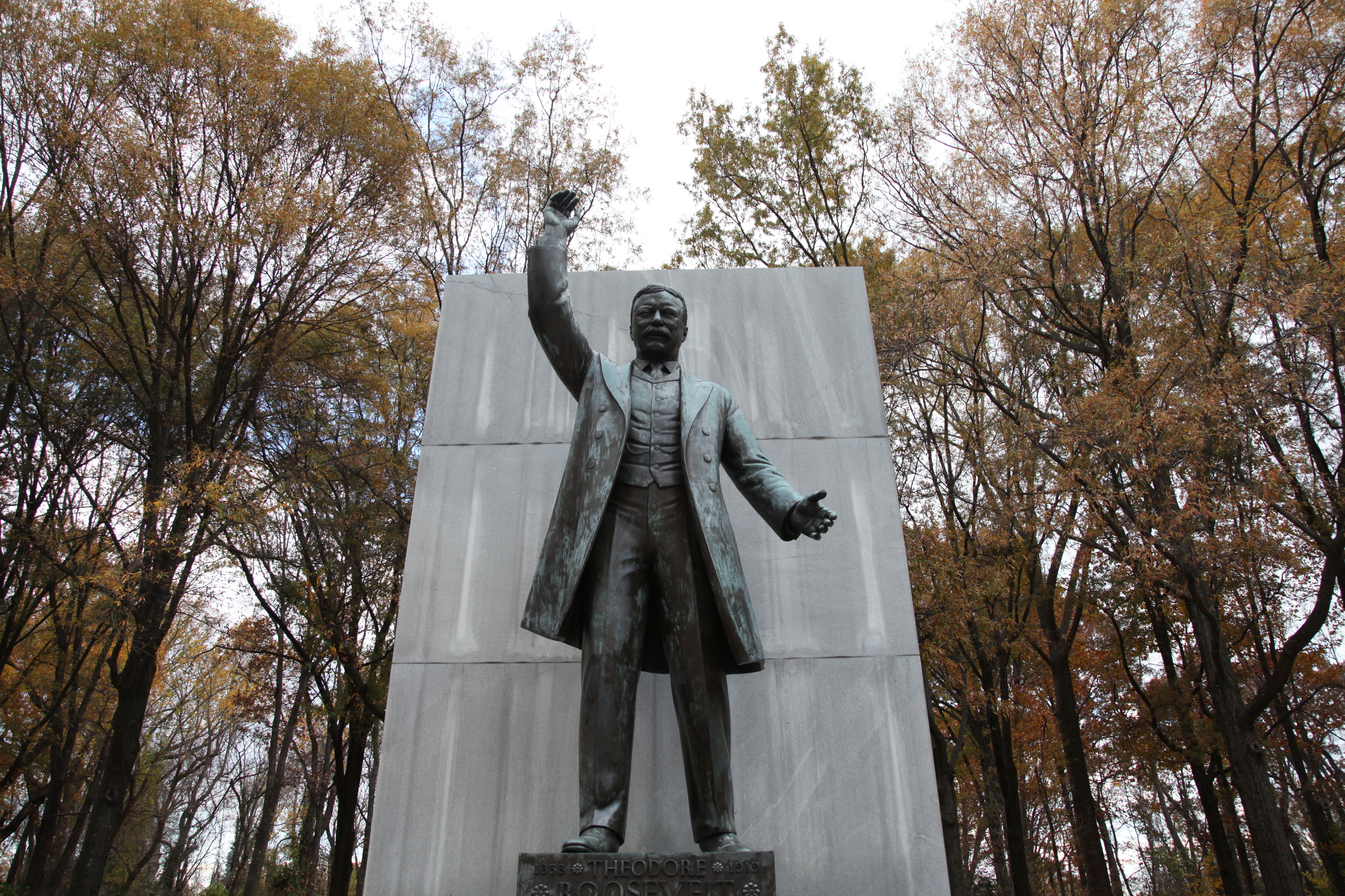 A bronze statue of Theodore Roosevelt standing and pointing.