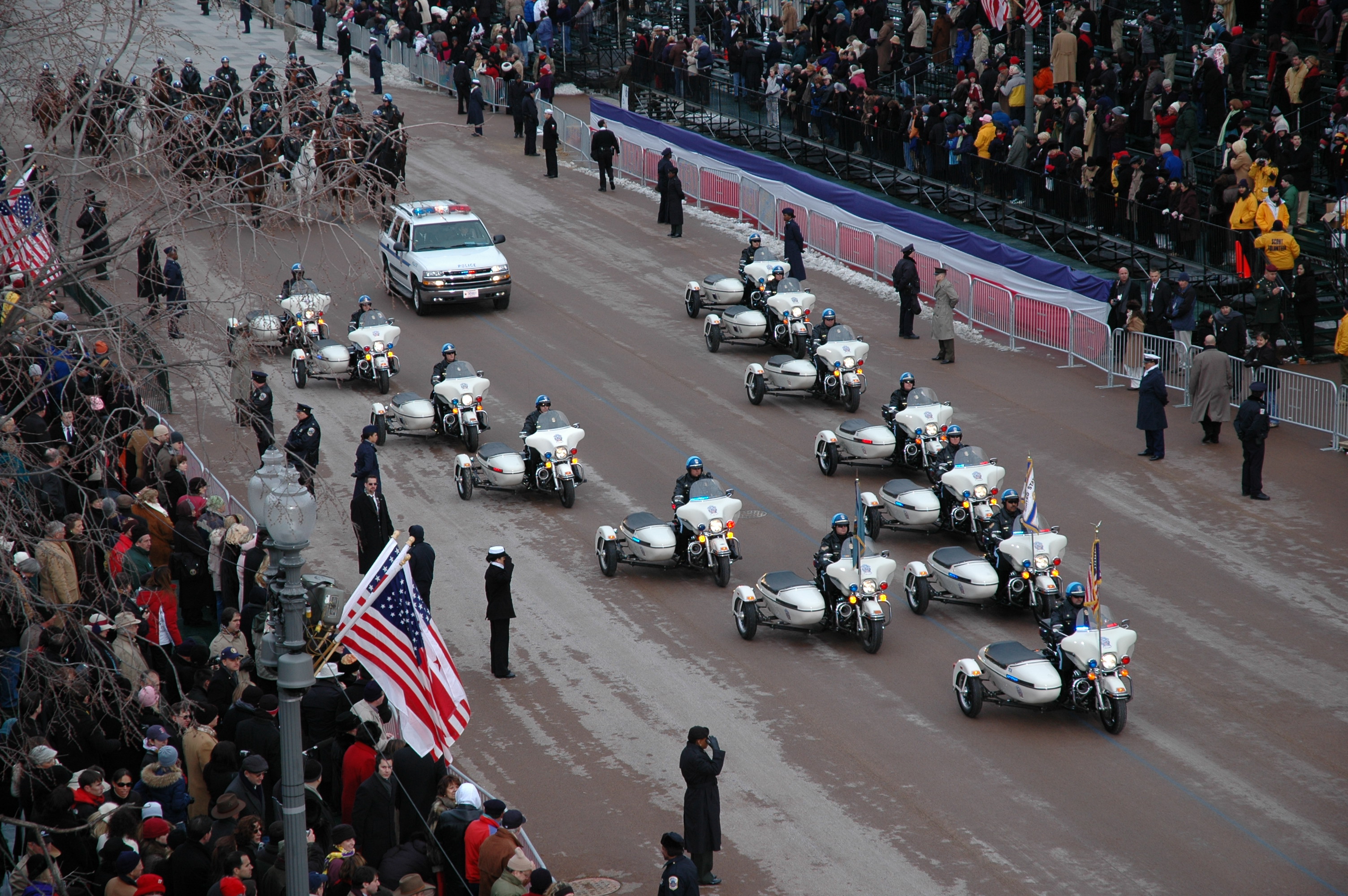 Motorcycles pass by a crowd in a parade.