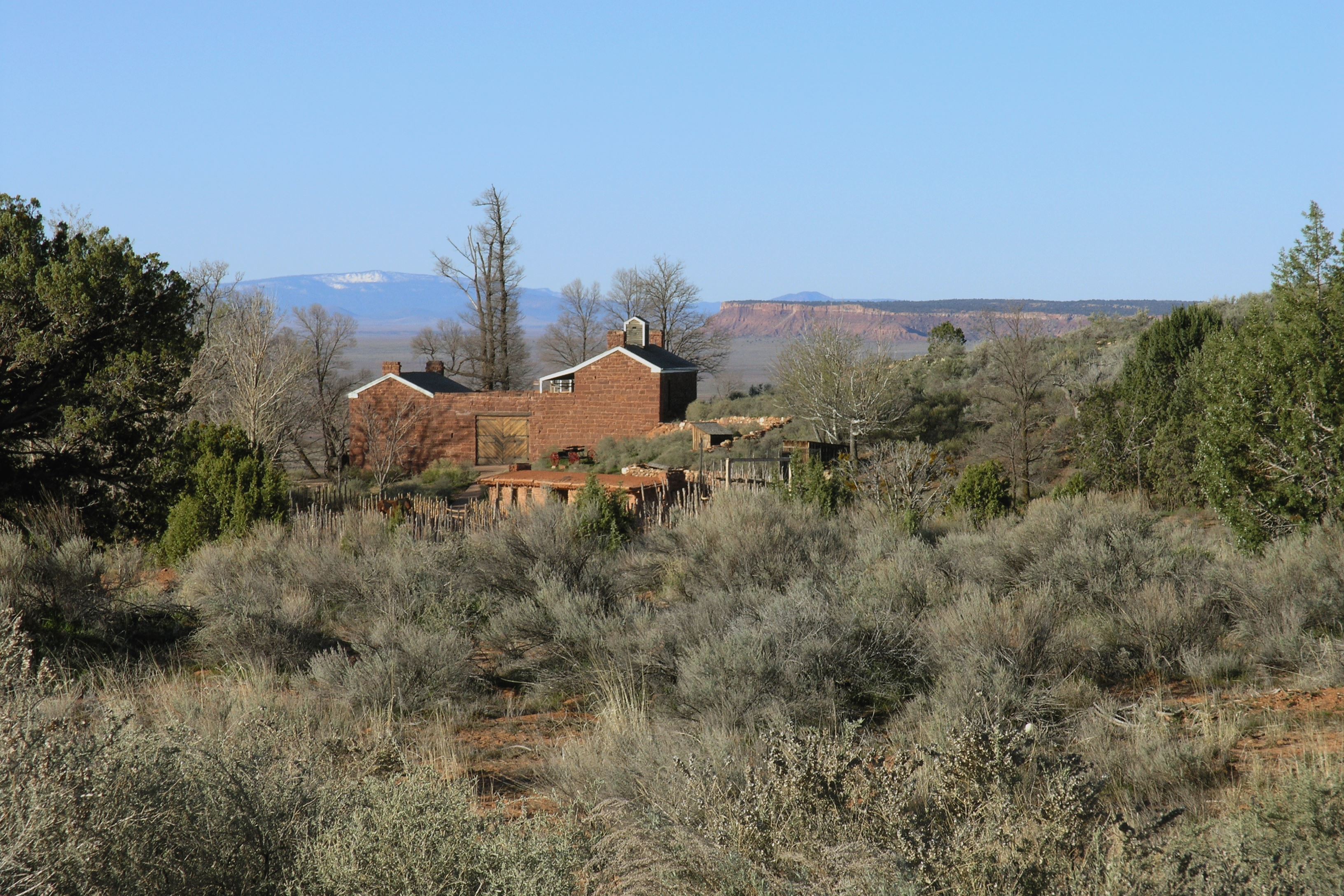 A sandstone fort rests between desert scrub in the foreground and a mountain in the distance.