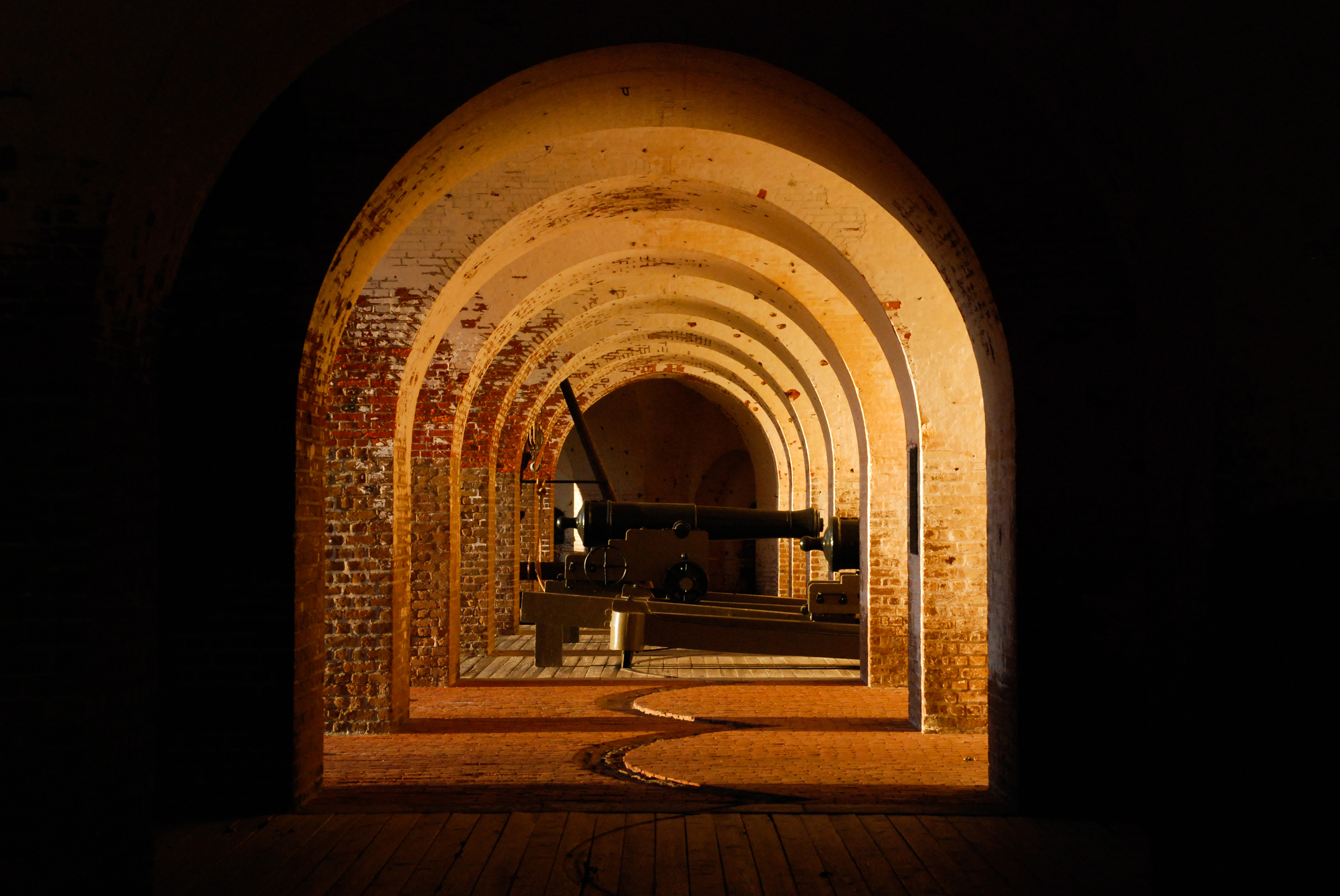 The brick of the fort glow in the late afternoon light. The arches inside the fort reveal a cannon i