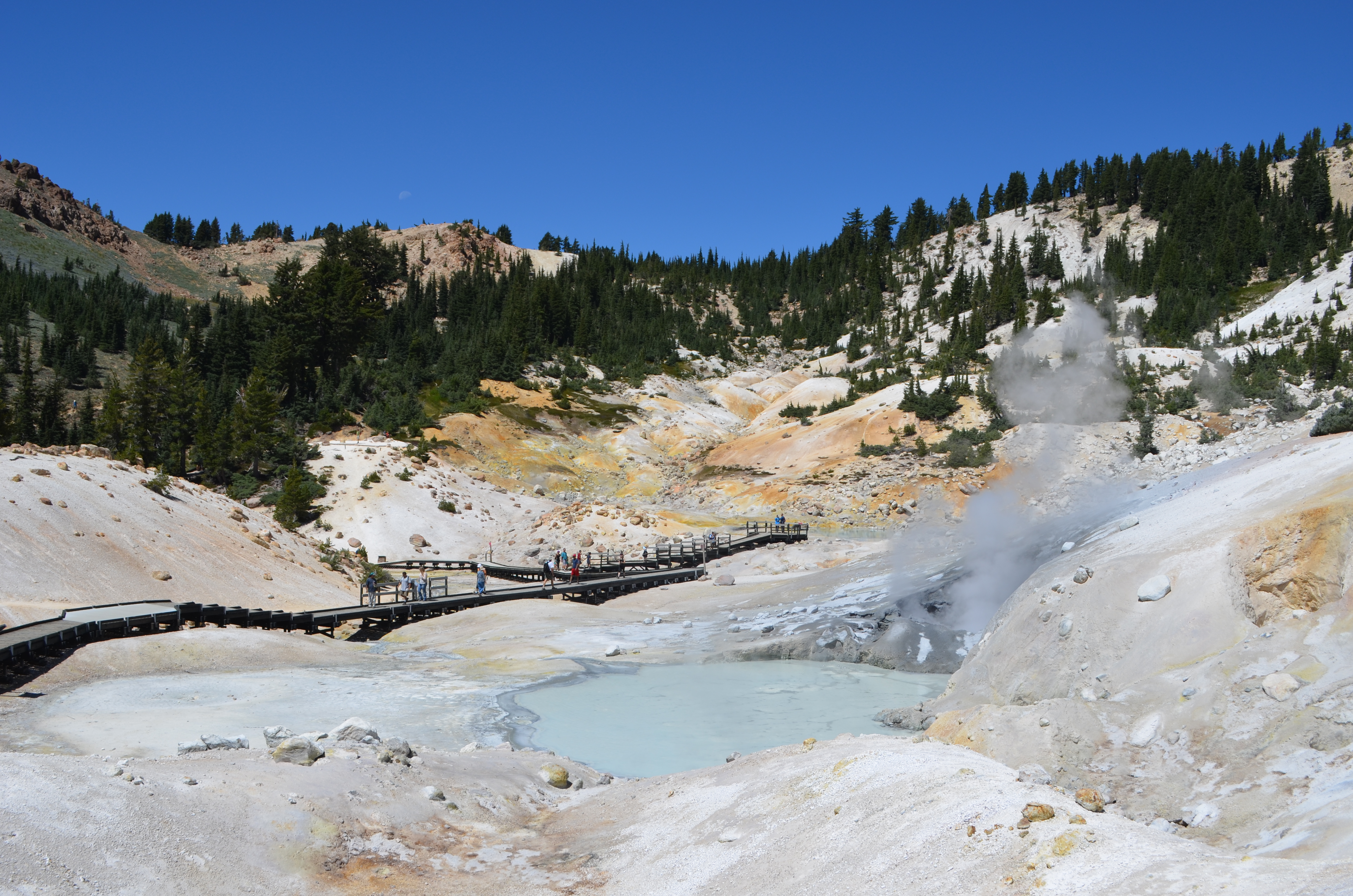 A boardwalk passes through a colorful, steaming hydrothermal basin.