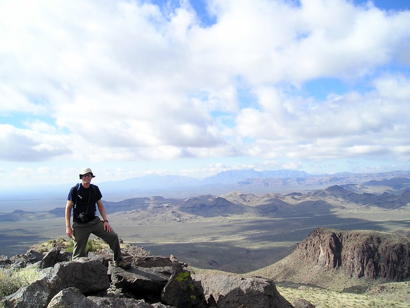 Stunning Vistas A man standing on a mountain peak in front of a wide desert landscape