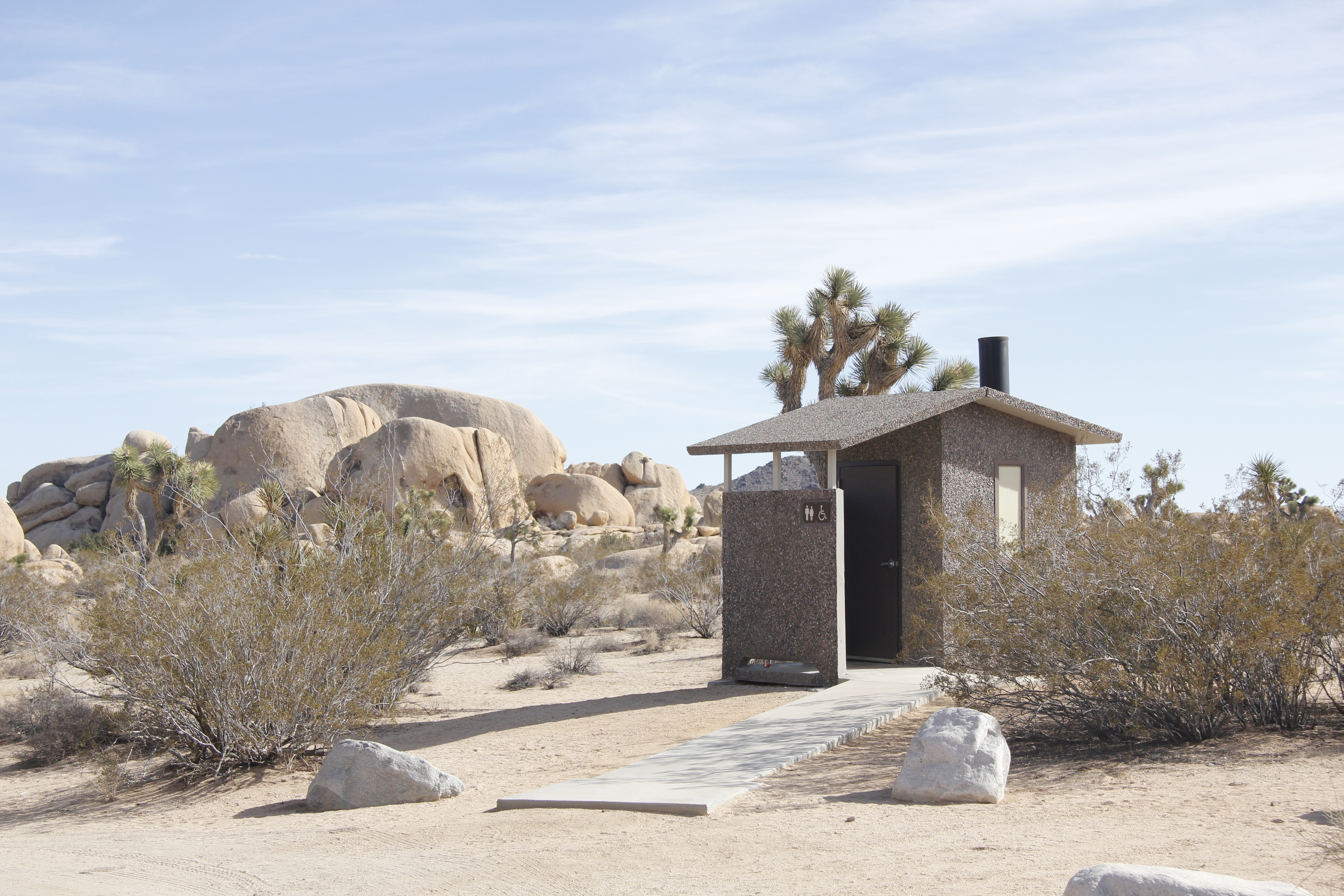 A paved path leads to a vault toilet.