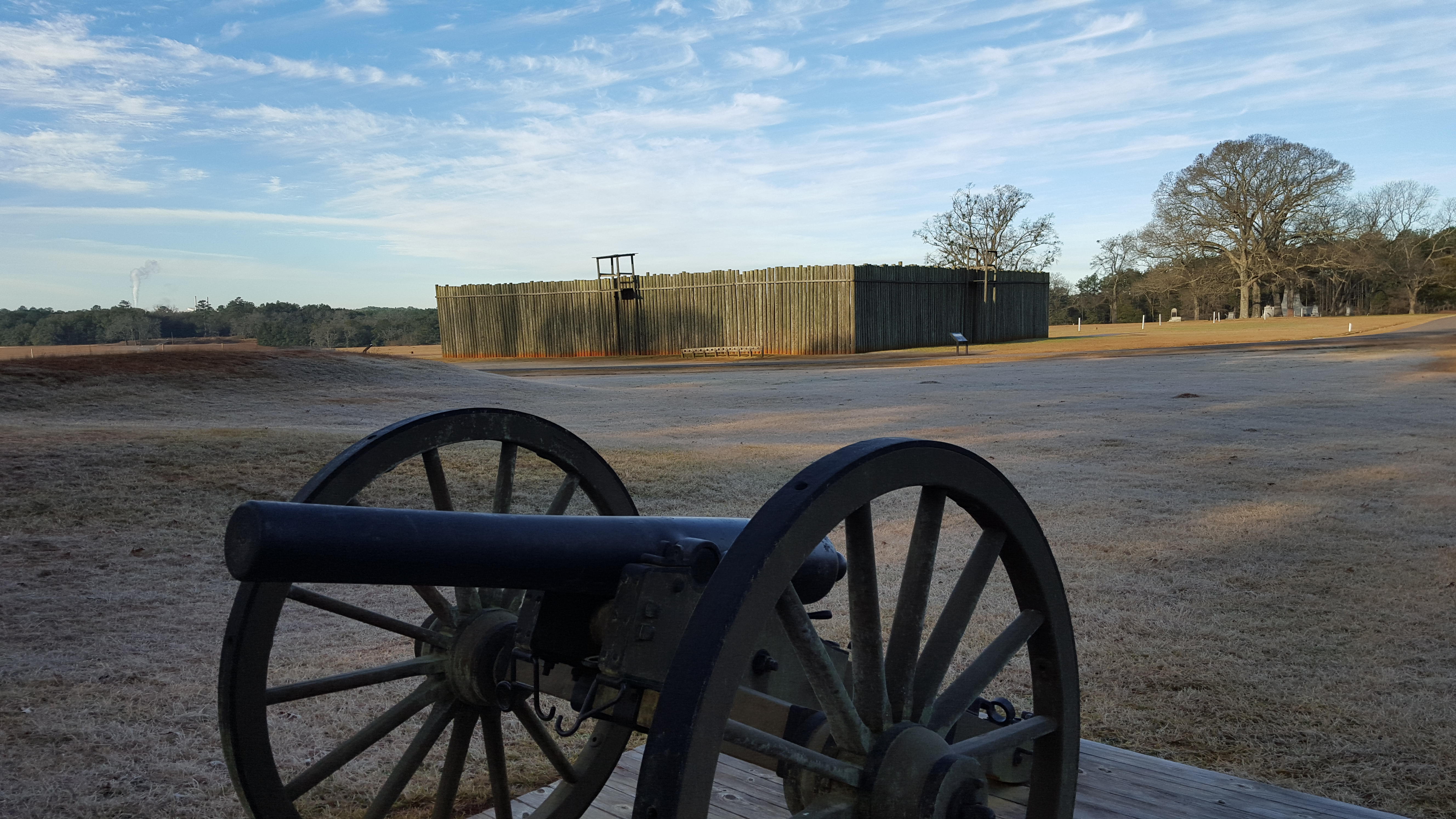 A cannon sits out in front of a replica of part of the wooden stockade walls once at Andersonville