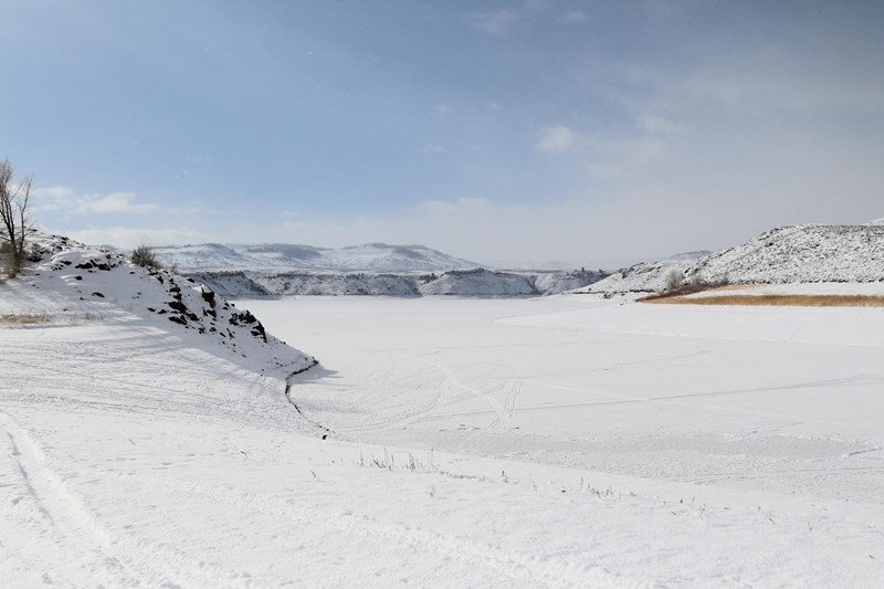 Frozen over body of water with snow covering it. Mesas are on the edge.