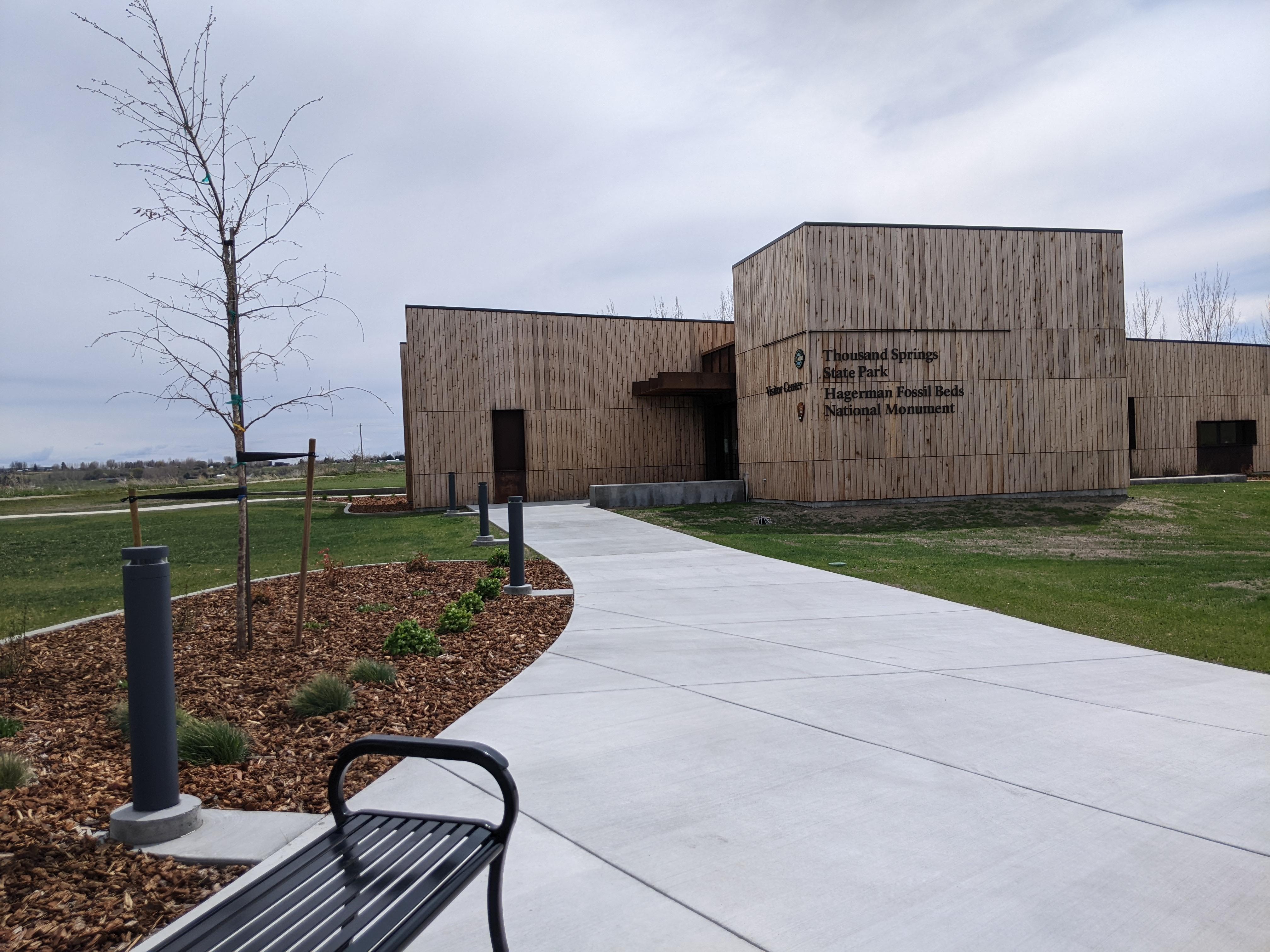 A sidewalk leads to a boxy, wood-paneled building labelled as "visitor center"