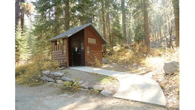 A sloping concrete path leads to a primitive toilet
