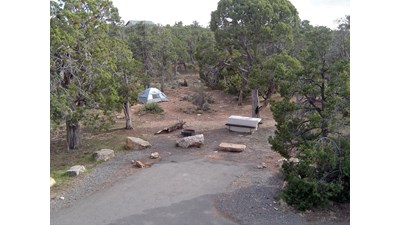 An empty campsite containing only a tent, draped picnic table, and fire ring