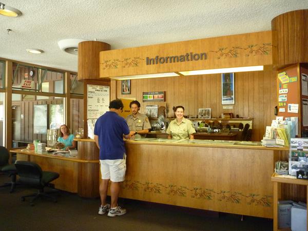 A visitor stands at the information desk, where a park volunteer and ranger work to answer questions