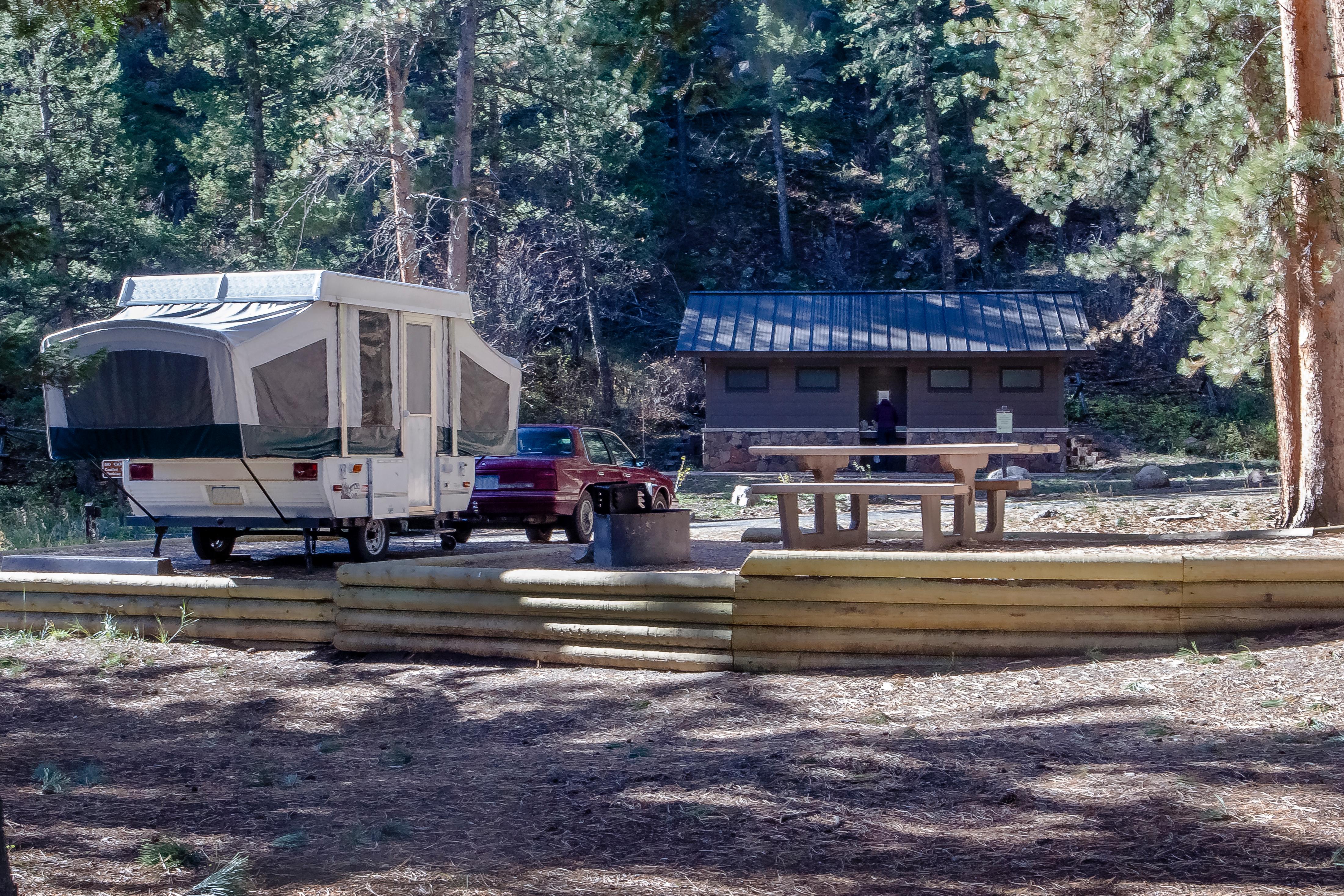 Popup camper at campsite with picnic table and comfort station