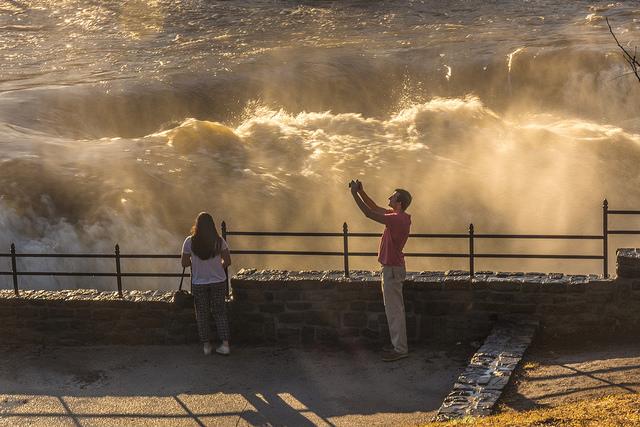 Man overlooking the falls while taking a selfie