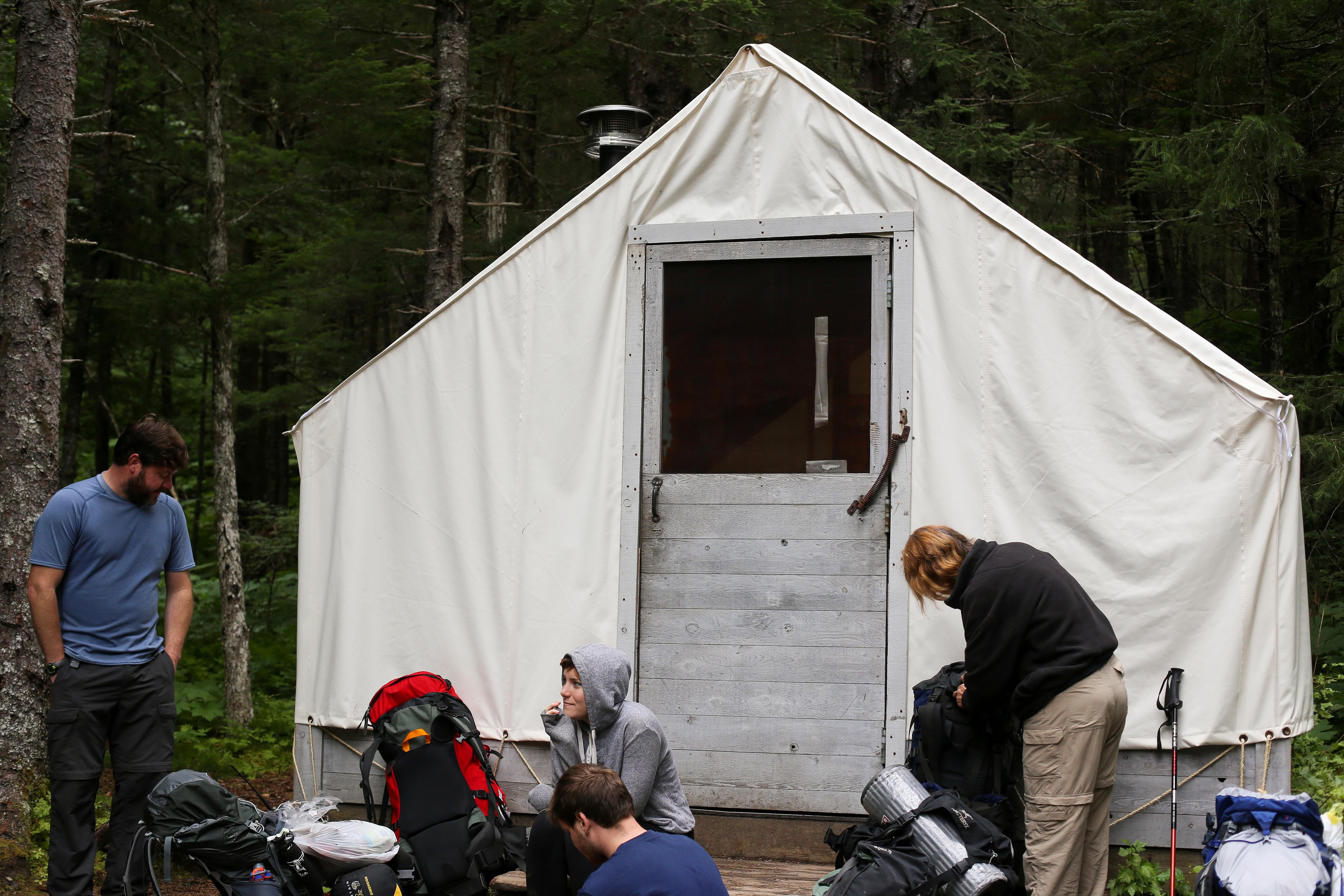 People gather near a white canvas tent