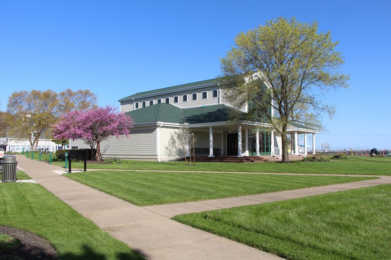 Visitor center porch and window A tan building with a 2-story center window, porch and columns, surrounded by trees and a lawn