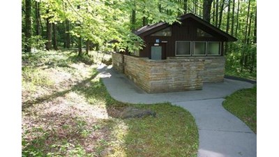 Paved walkway leads to a wooden restroom structure
