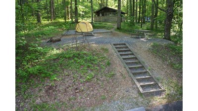 Steps lead to a tent only site occupied by a yellow tent