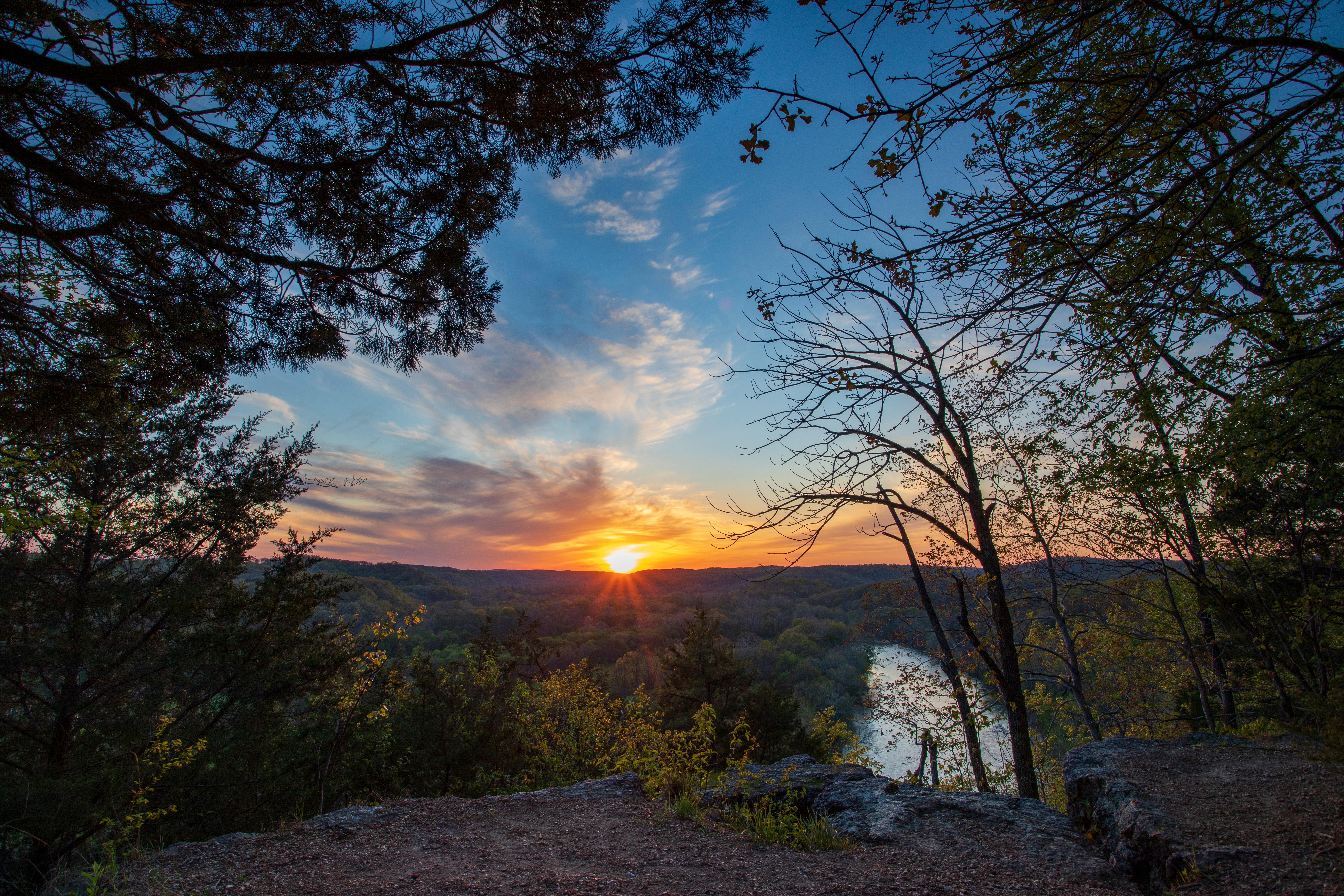 Sunset picture with high vantage point overlooking river with fall colors and sun setting in distanc