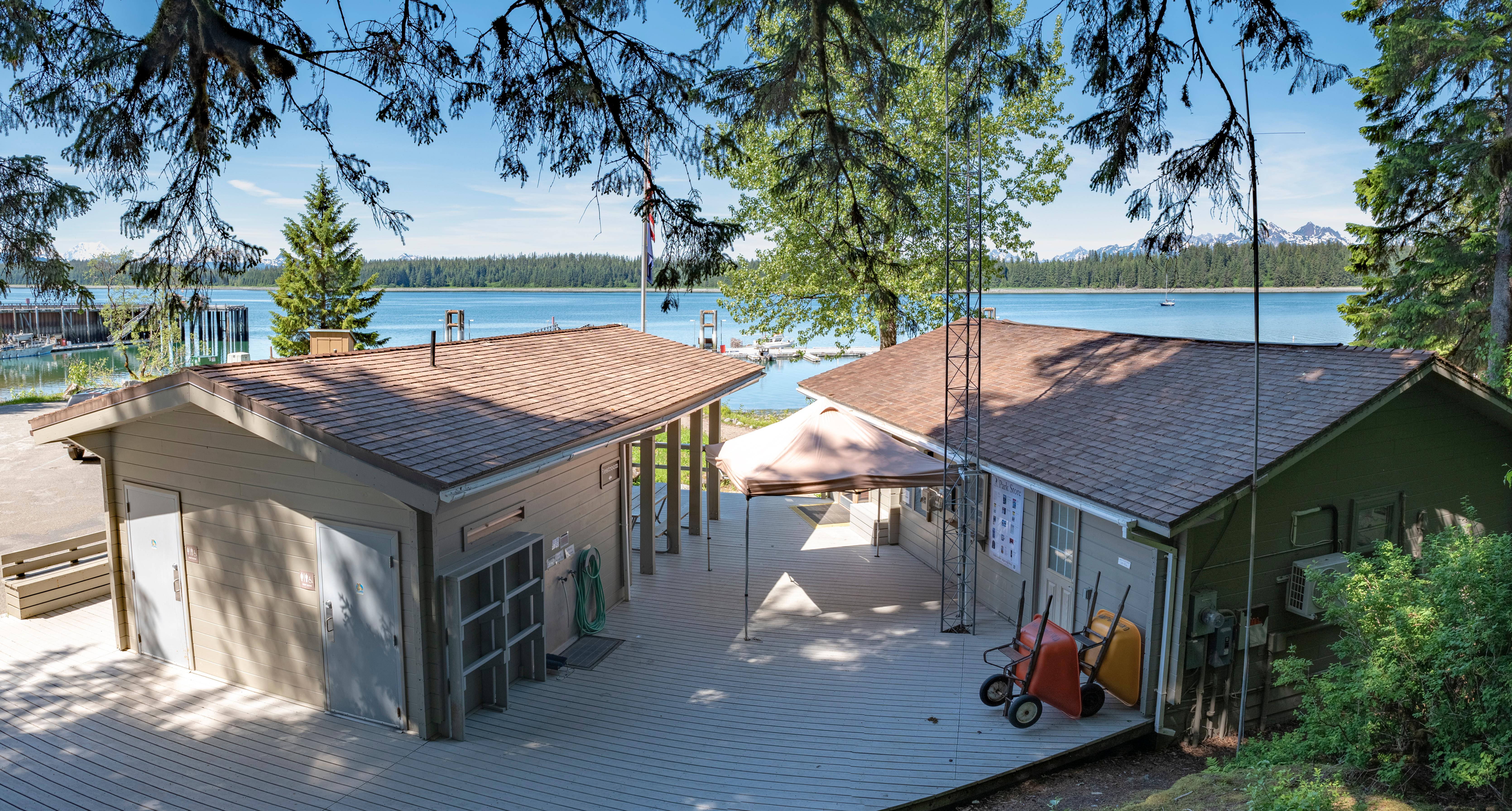 Backside view of the VIS buildings and patio area. Bartlett Cove and water visible through trees