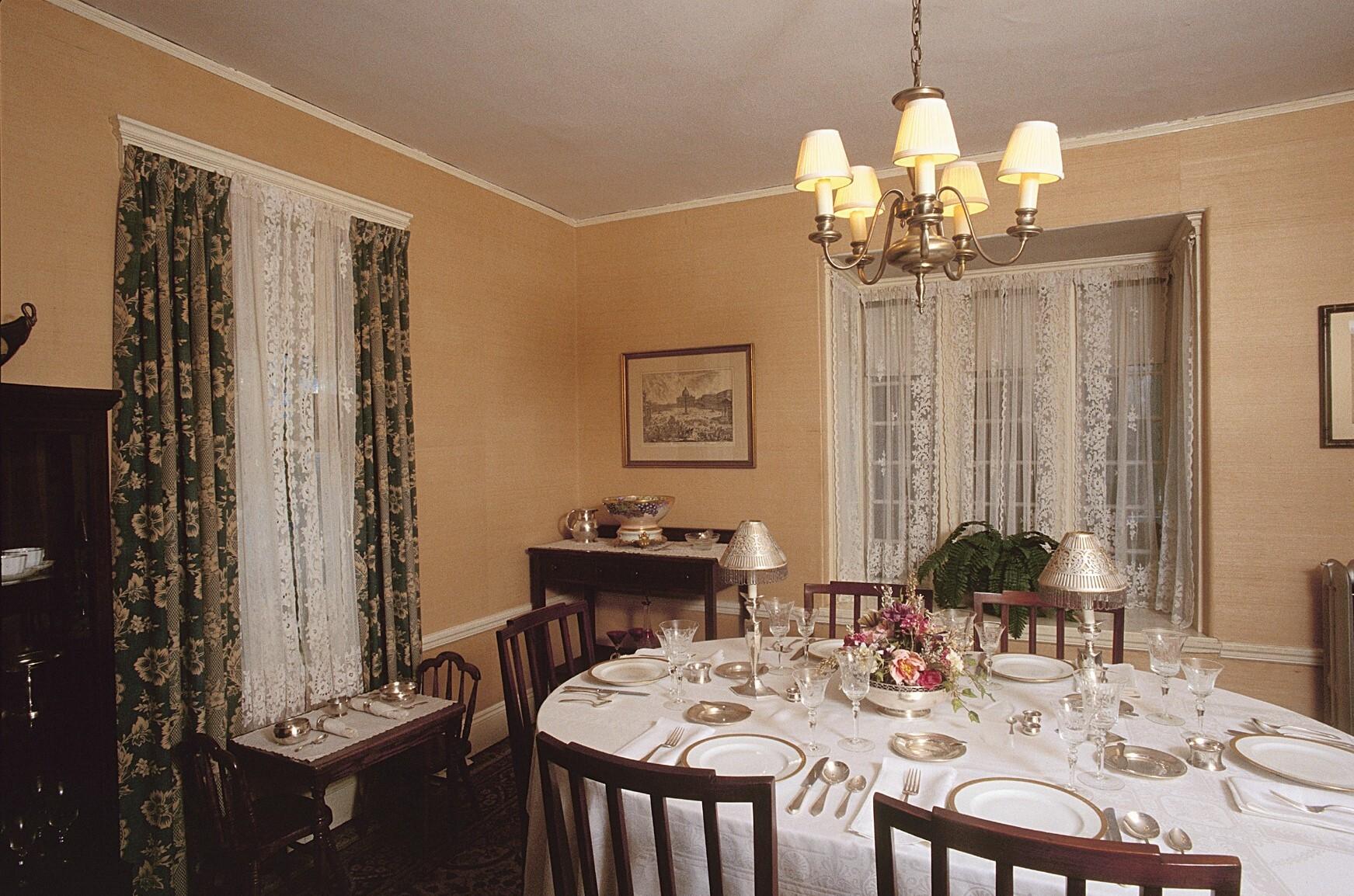 Dining room with oval dining table with six place settings of silver and fine china.