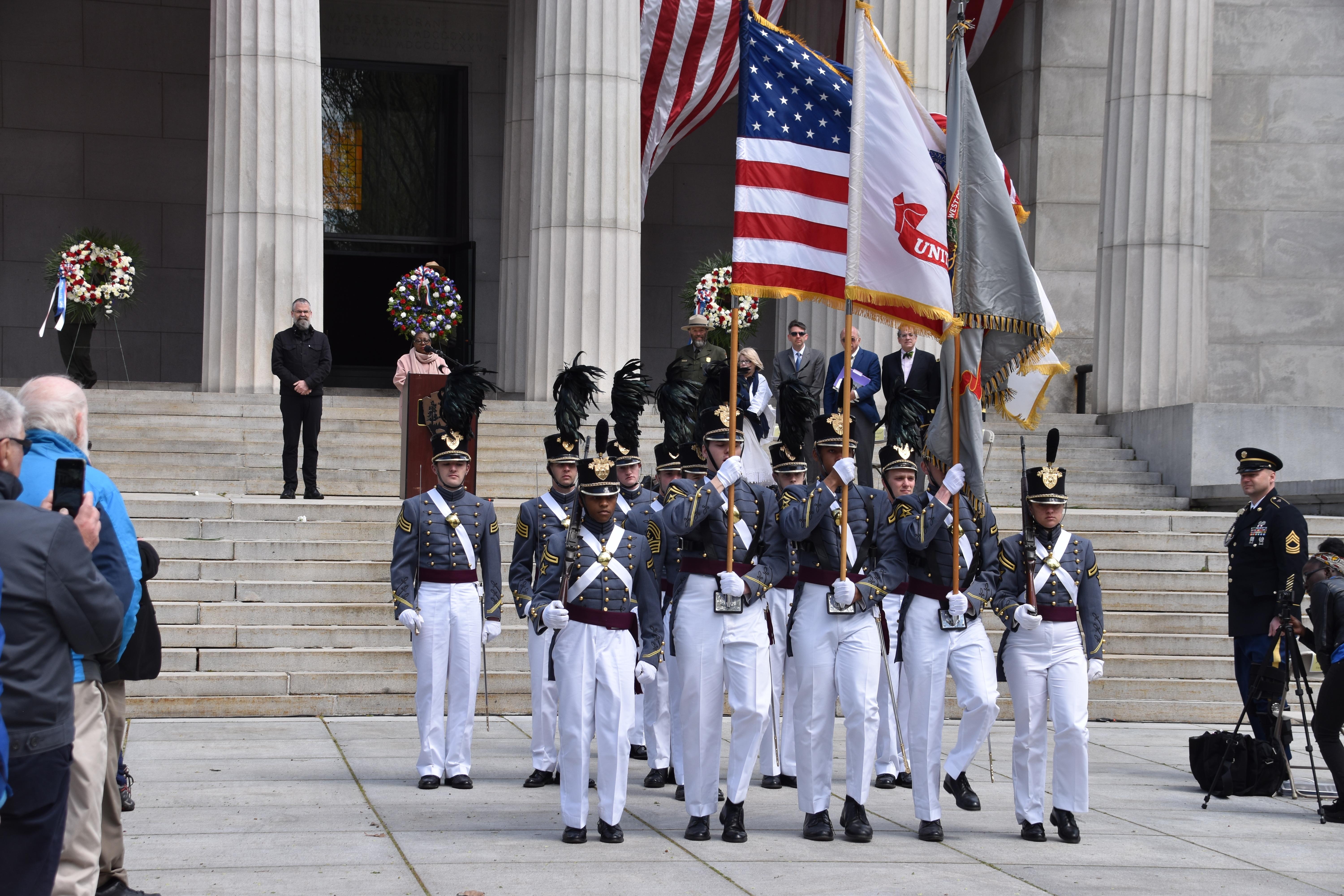 West Point Cadets in formal uniforms carrying three flags in front of the mausoleum