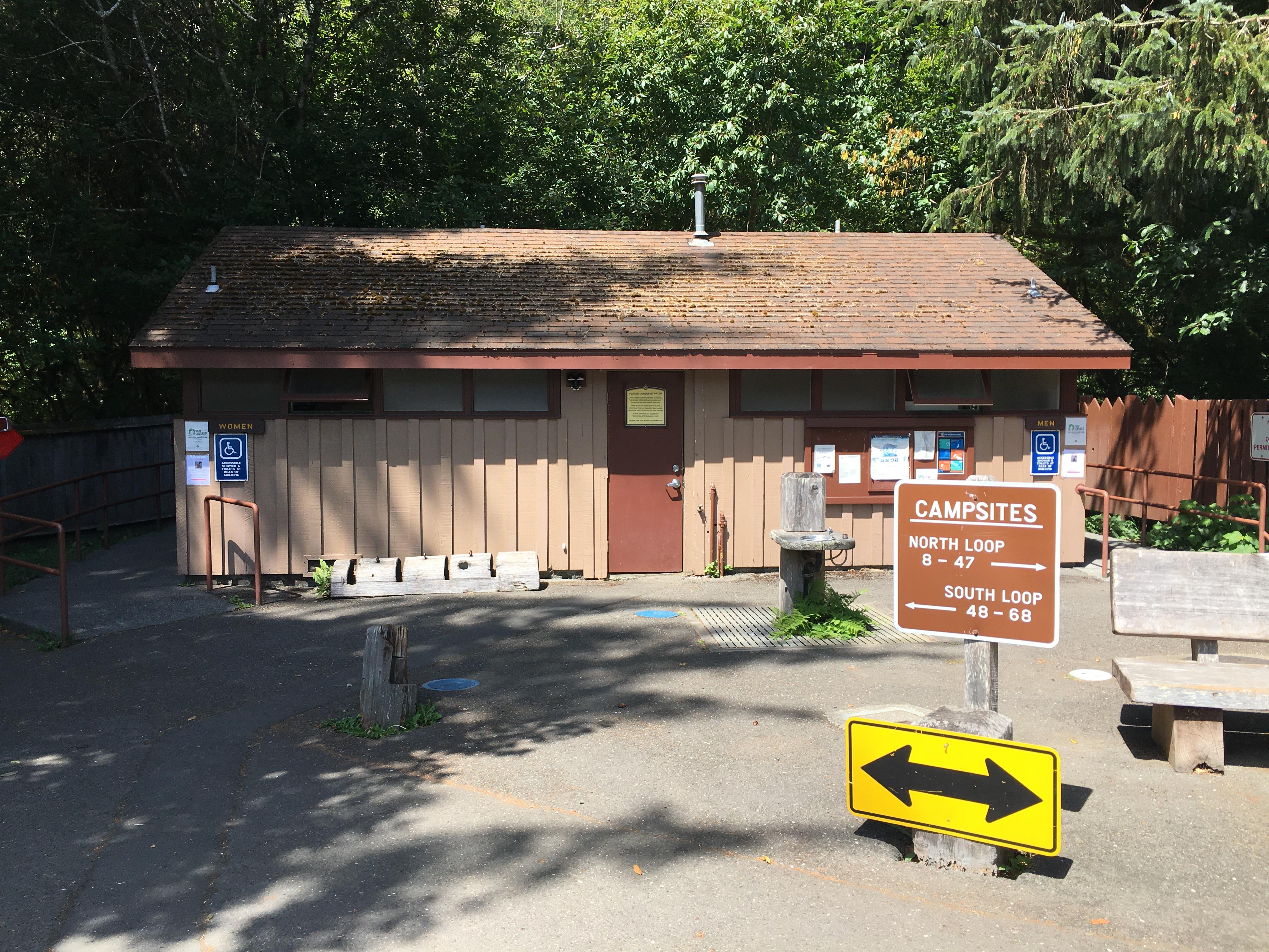 Brown building in front of redwood trees.